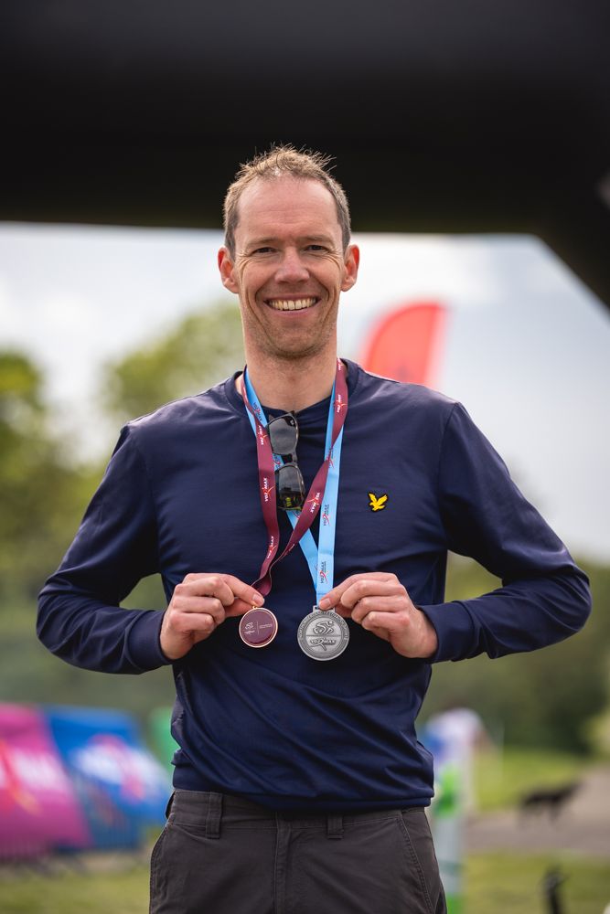 Triathlete smiling enjoying his winners medals.