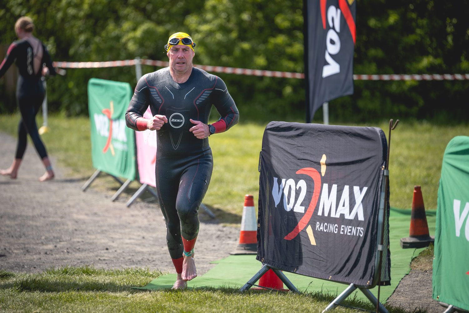 A man running in a triathlon with his swimming outfit on.