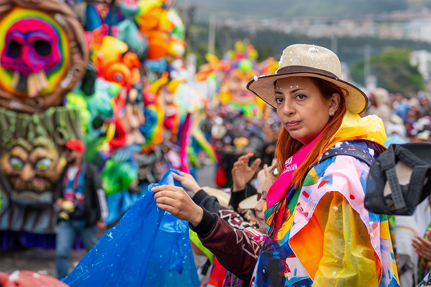 A member of the crowd, at the carnival, enjoying herself with the floats passing by in the background.