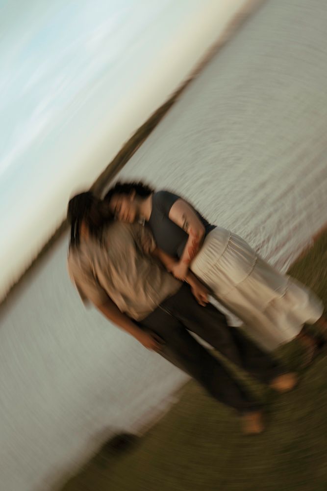 Couple embracing and kissing near waterfront in artistic motion blur romantic photo.