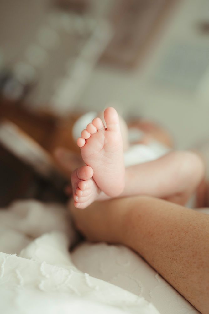 Soft focus shot of newborn baby feet resting on white blanket.