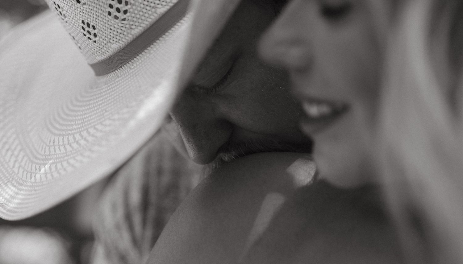 Black and white photo of a woman wearing a white cowboy hat, with soft focus and romantic lighting.