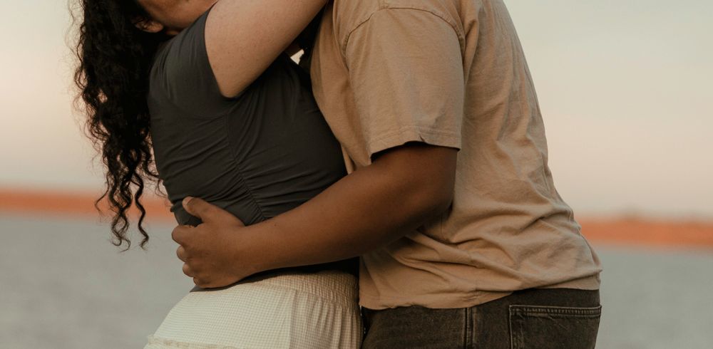 Couple sharing a close tender embrace outdoors in romantic engagement portrait session.