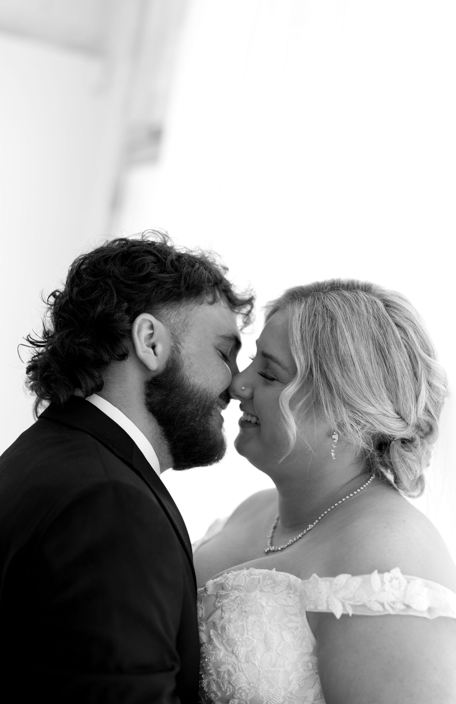 Intimate black and white close-up of bride and bearded groom sharing a romantic kiss.