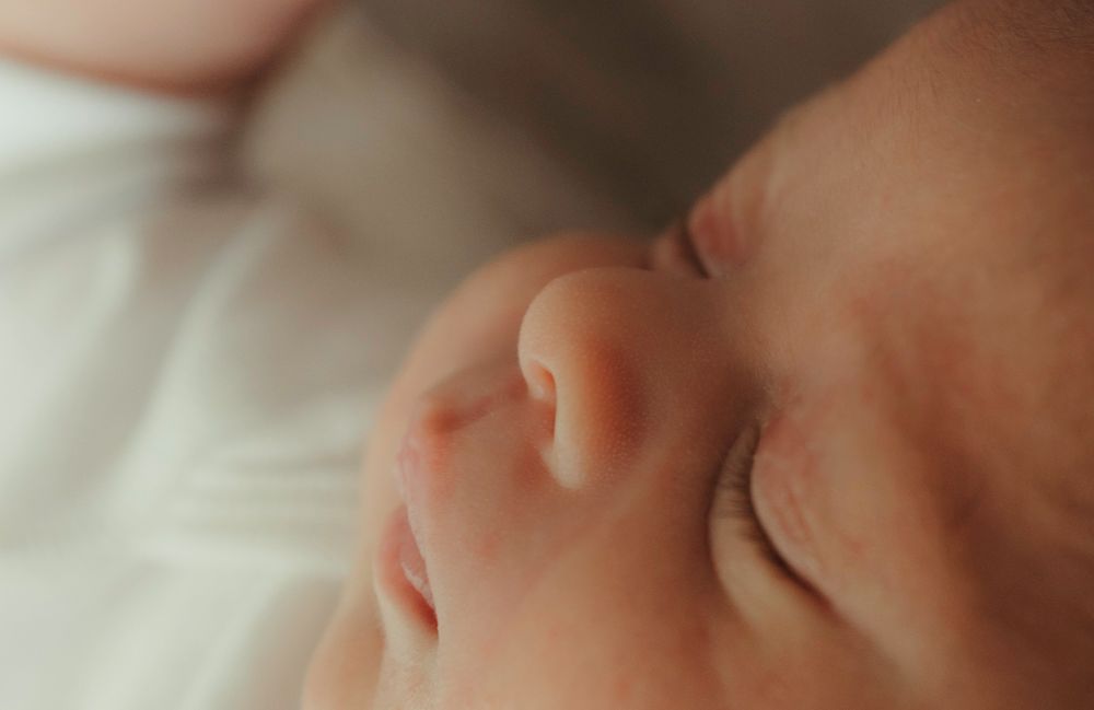 Peaceful sleeping newborn baby with tiny fingers and delicate features in soft focus close-up.
