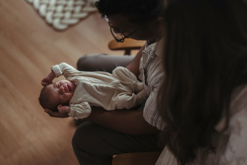 Mother lovingly gazing at her smiling newborn baby held in her arms from above.