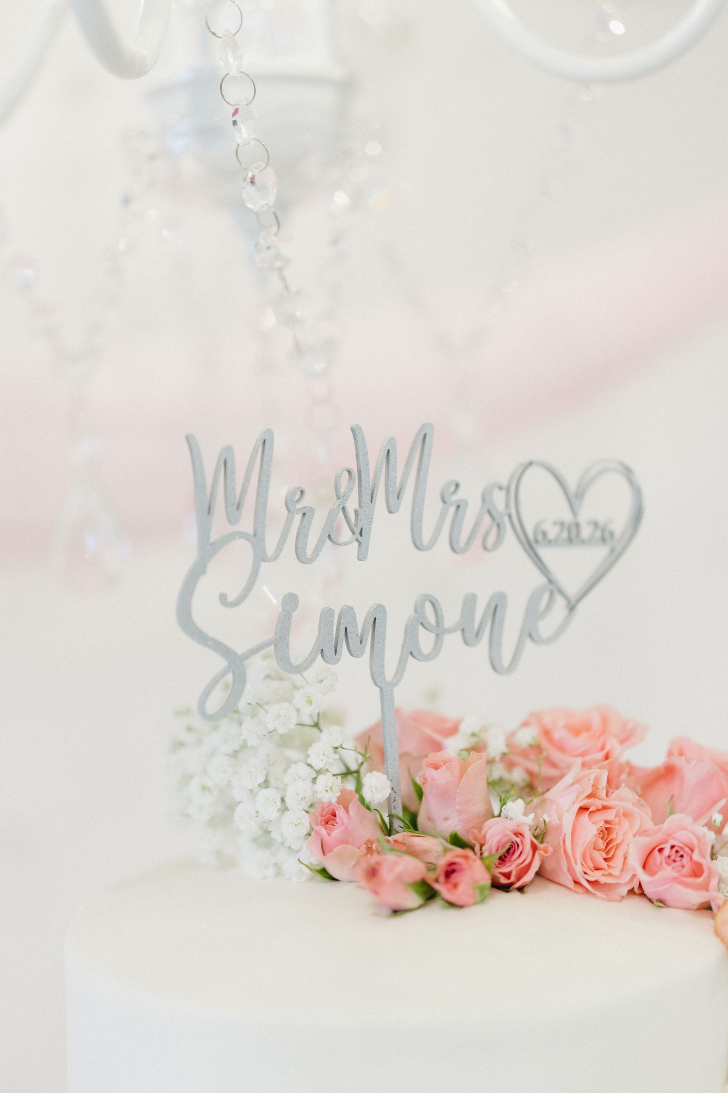 Elegant Mr and Mrs Simone wedding cake topper with pink roses on a white tiered cake.