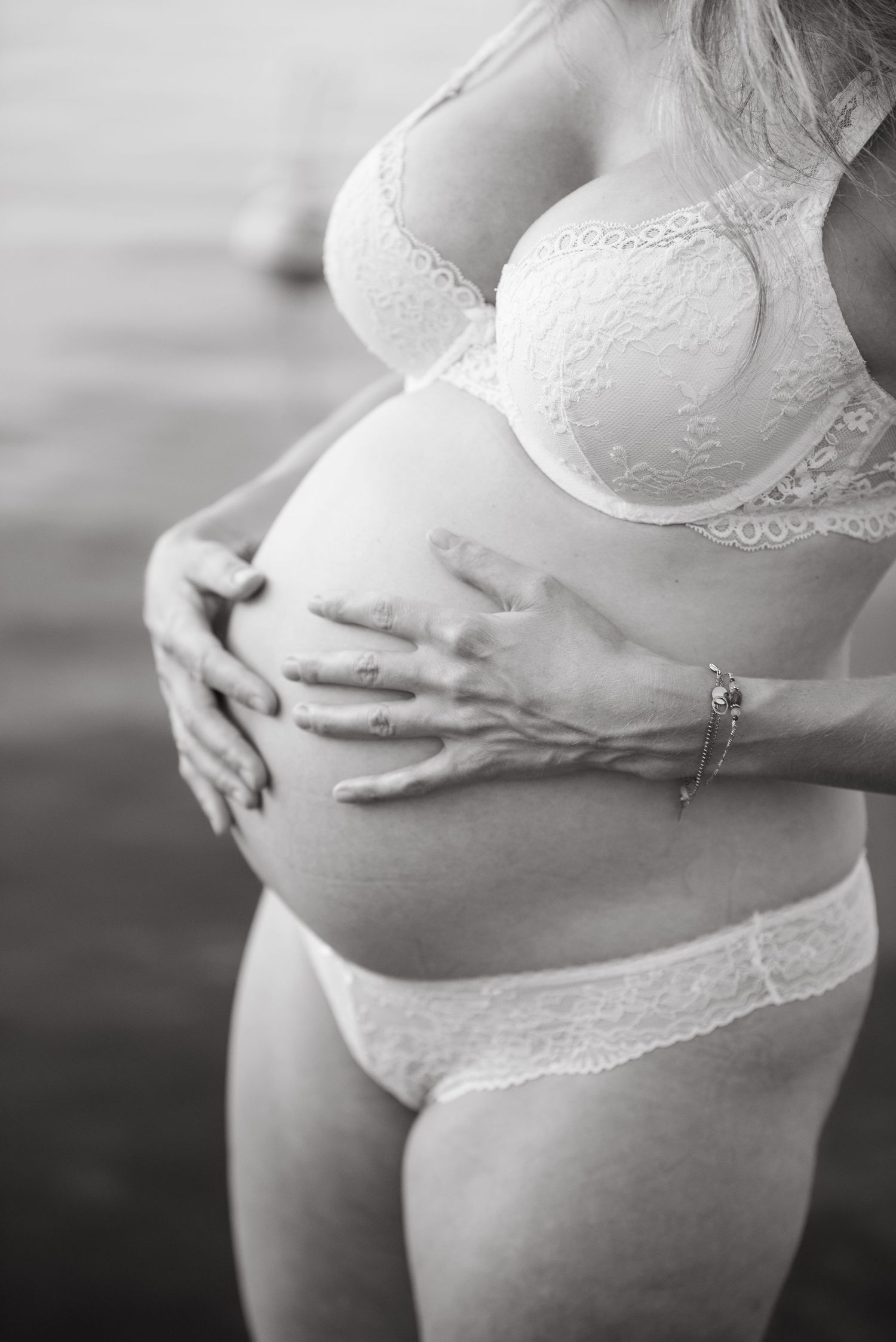Gros plan en noir et blanc sur le ventre rond d’une femme enceinte lors d’une séance grossesse