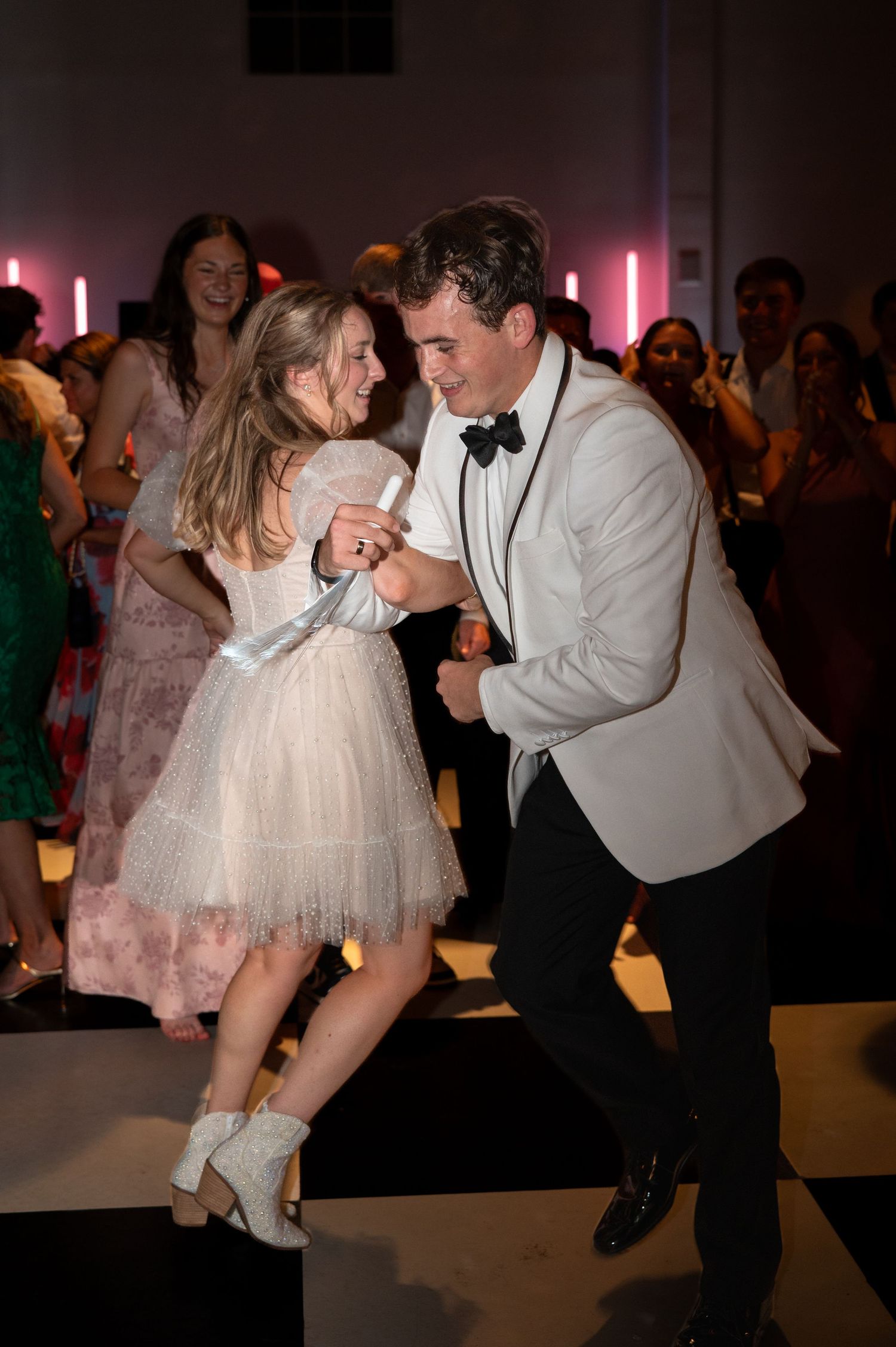 Bride and groom dance together on black and white dance floor.