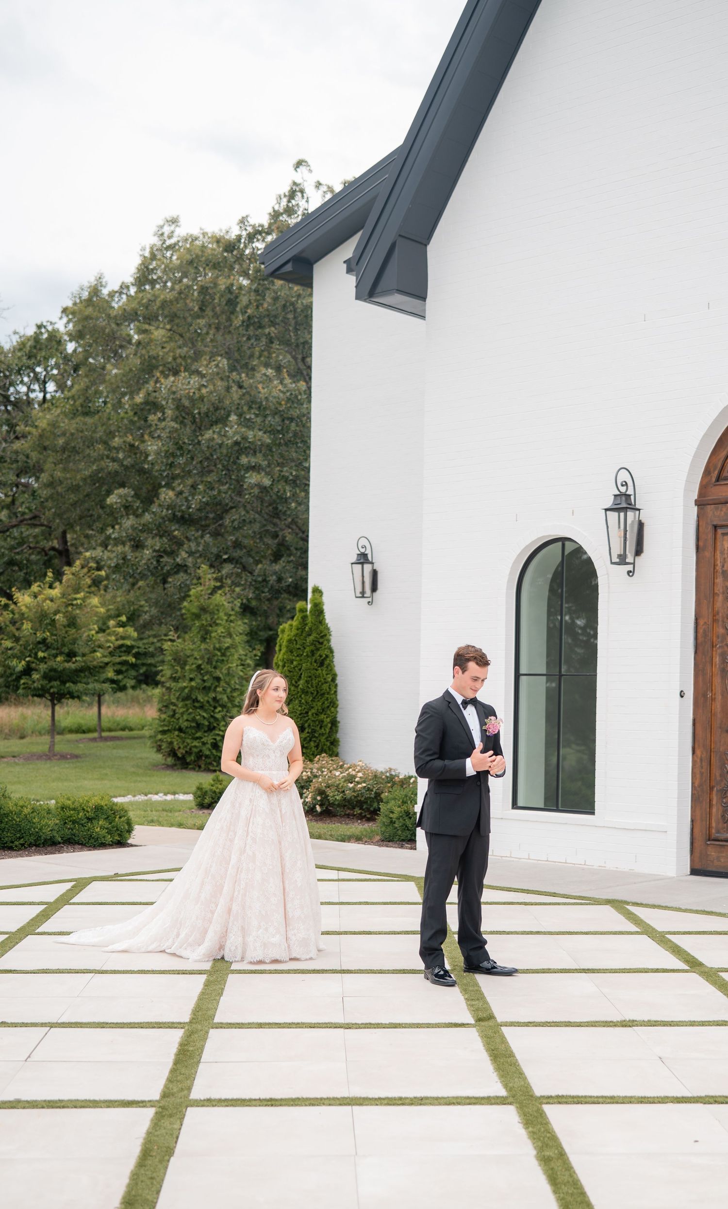 Bride and groom share first look moment outside stunning white modern wedding venue chapel.
