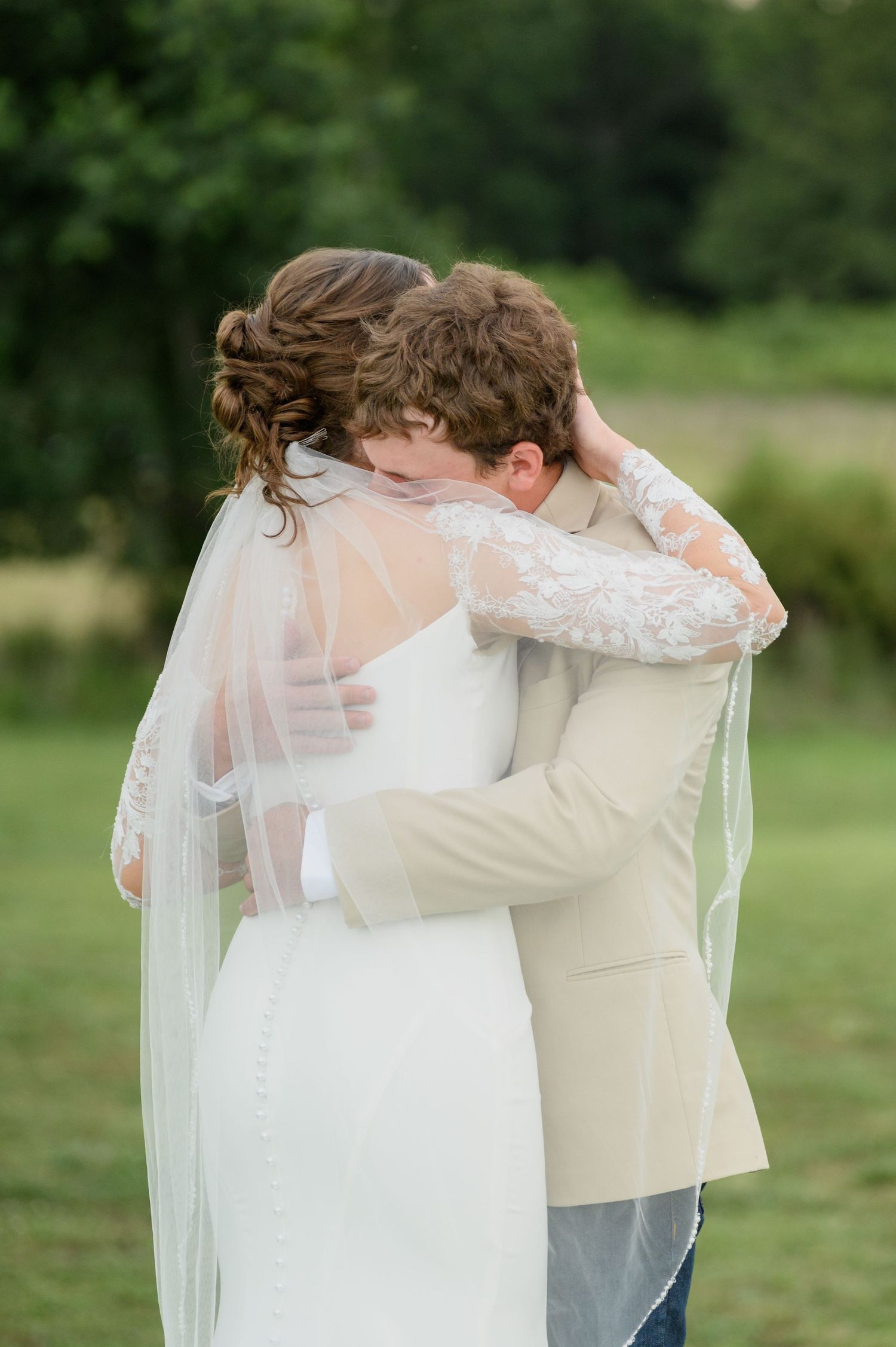 Bride and groom share an emotional first look embrace outdoors on their wedding day.