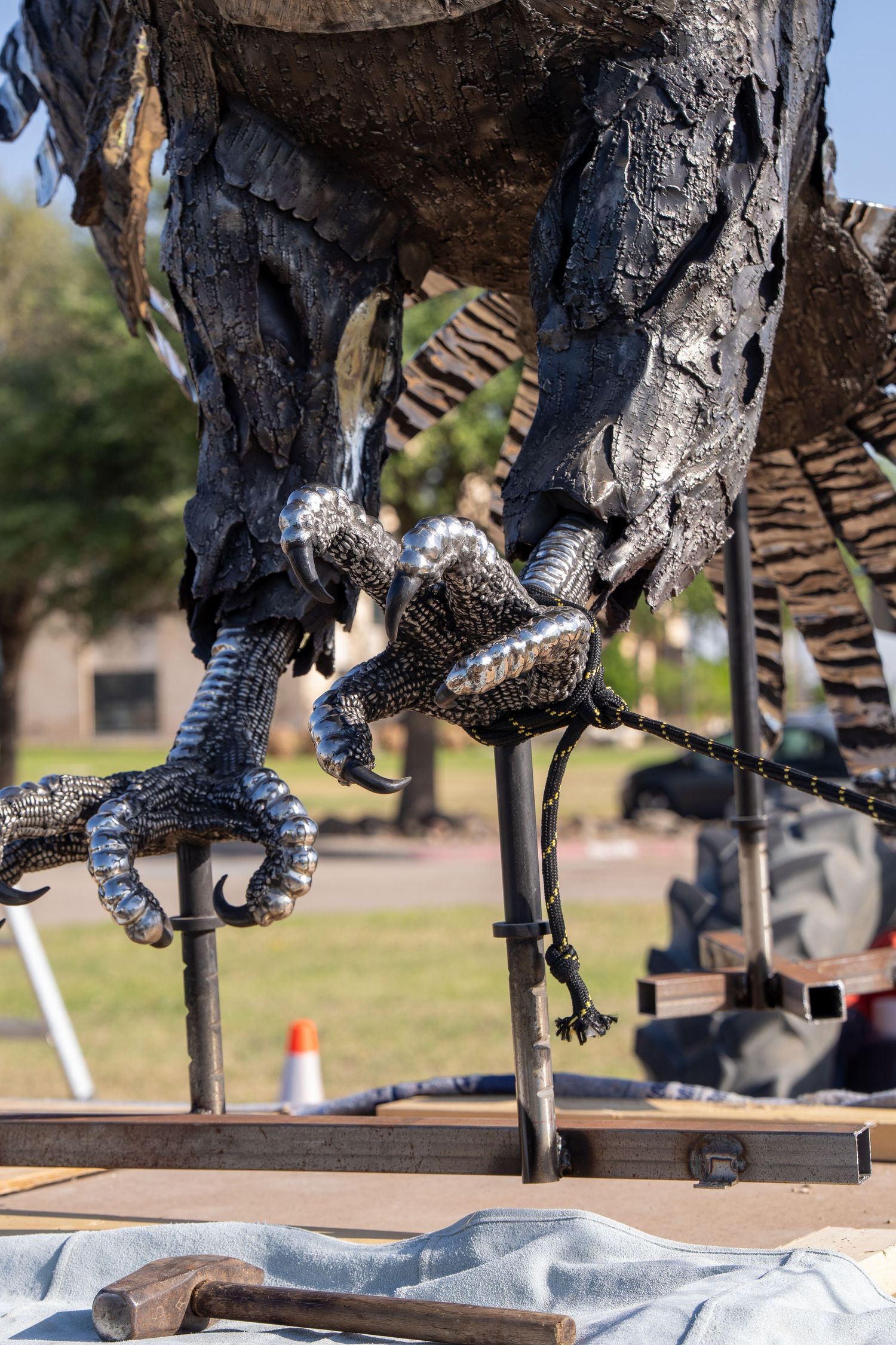 Close-up of metallic bird talons on a large outdoor sculpture being installed on a platform.
