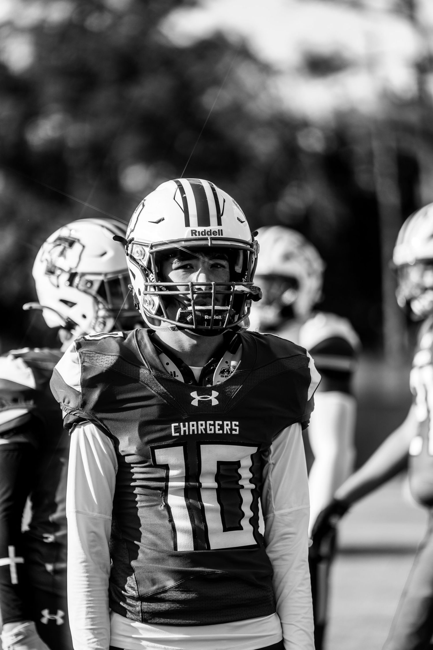 Black and white photo of a football player wearing a Chargers jersey number 10 and Riddell helmet on the field.