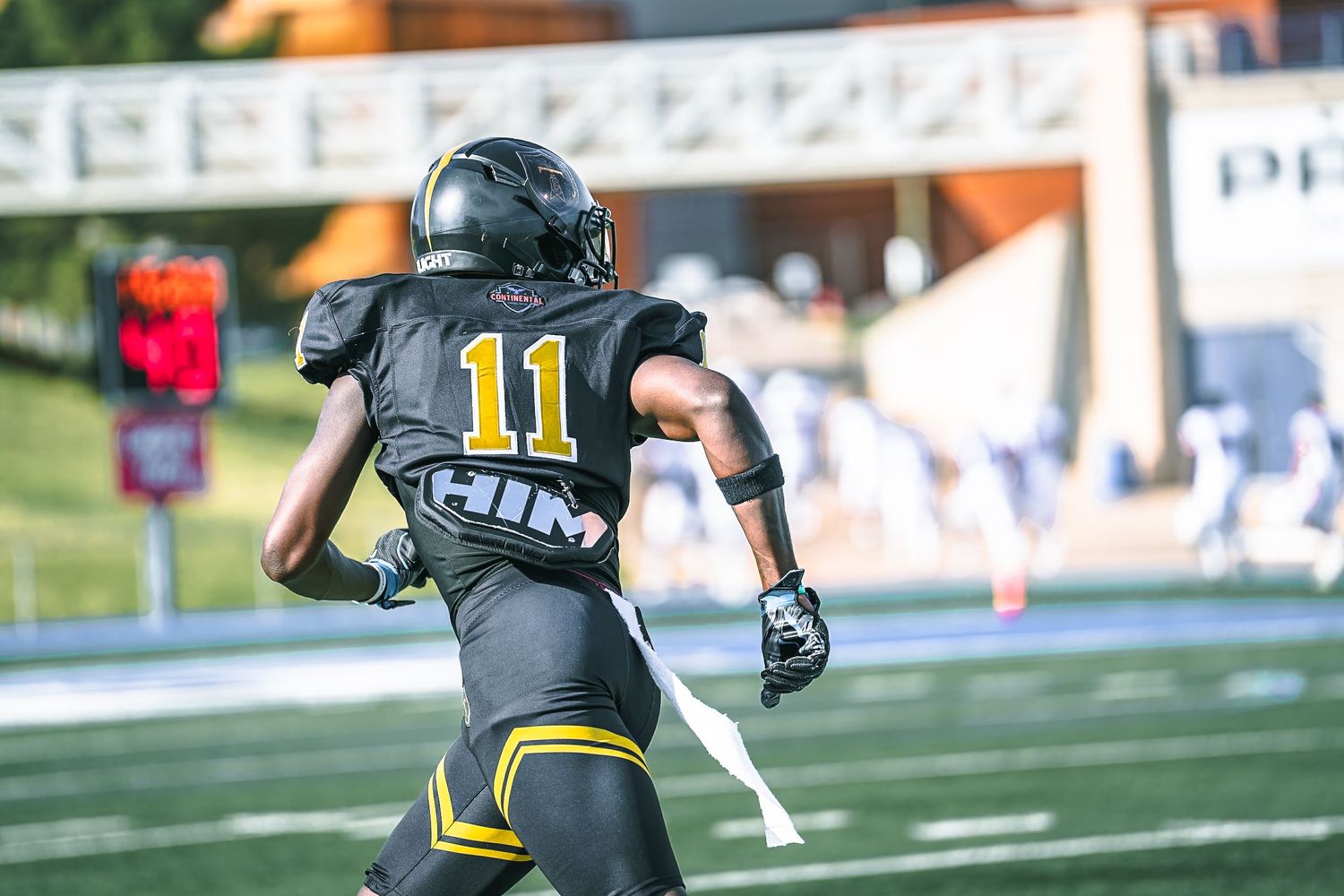 Tall City football player number 11 in black and gold uniform runs on the field during a game.