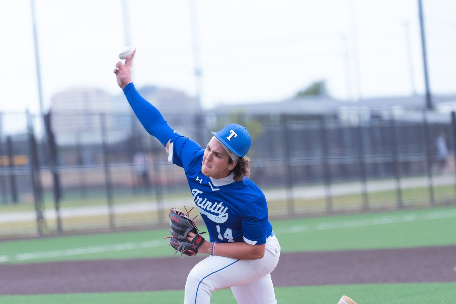Trinity baseball pitcher #14 in blue uniform delivers a pitch.
