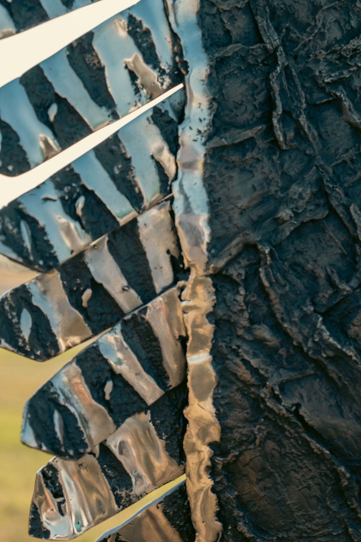 Close-up of a muddy off-road tire tread with dark textured rubber and reflective wet surfaces.