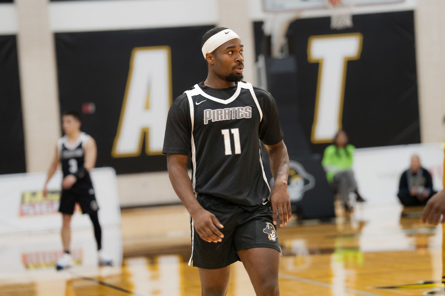 Basketball player wearing number 11 Phantoms jersey stands on indoor court during a game.