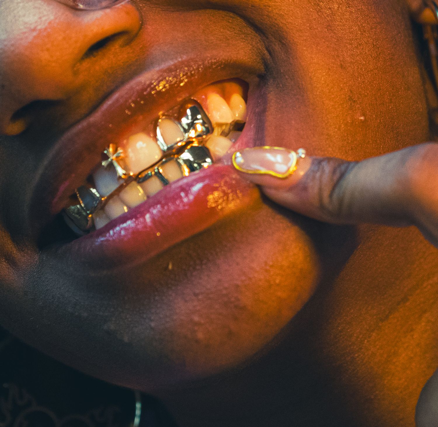 Close-up of person smiling with gold grillz dental jewelry.