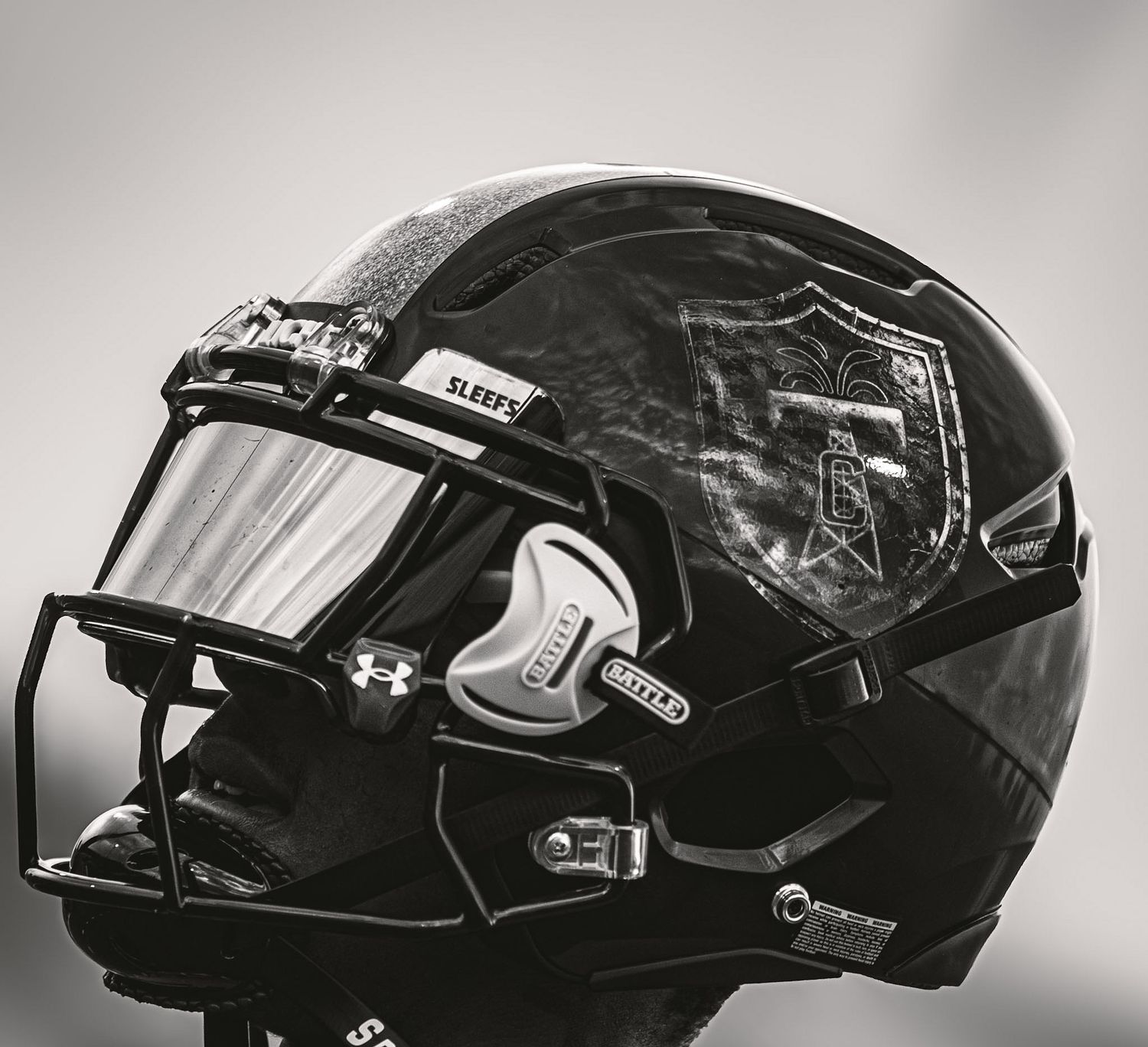 Close-up black and white photo of a black football helmet with face guard and visor.