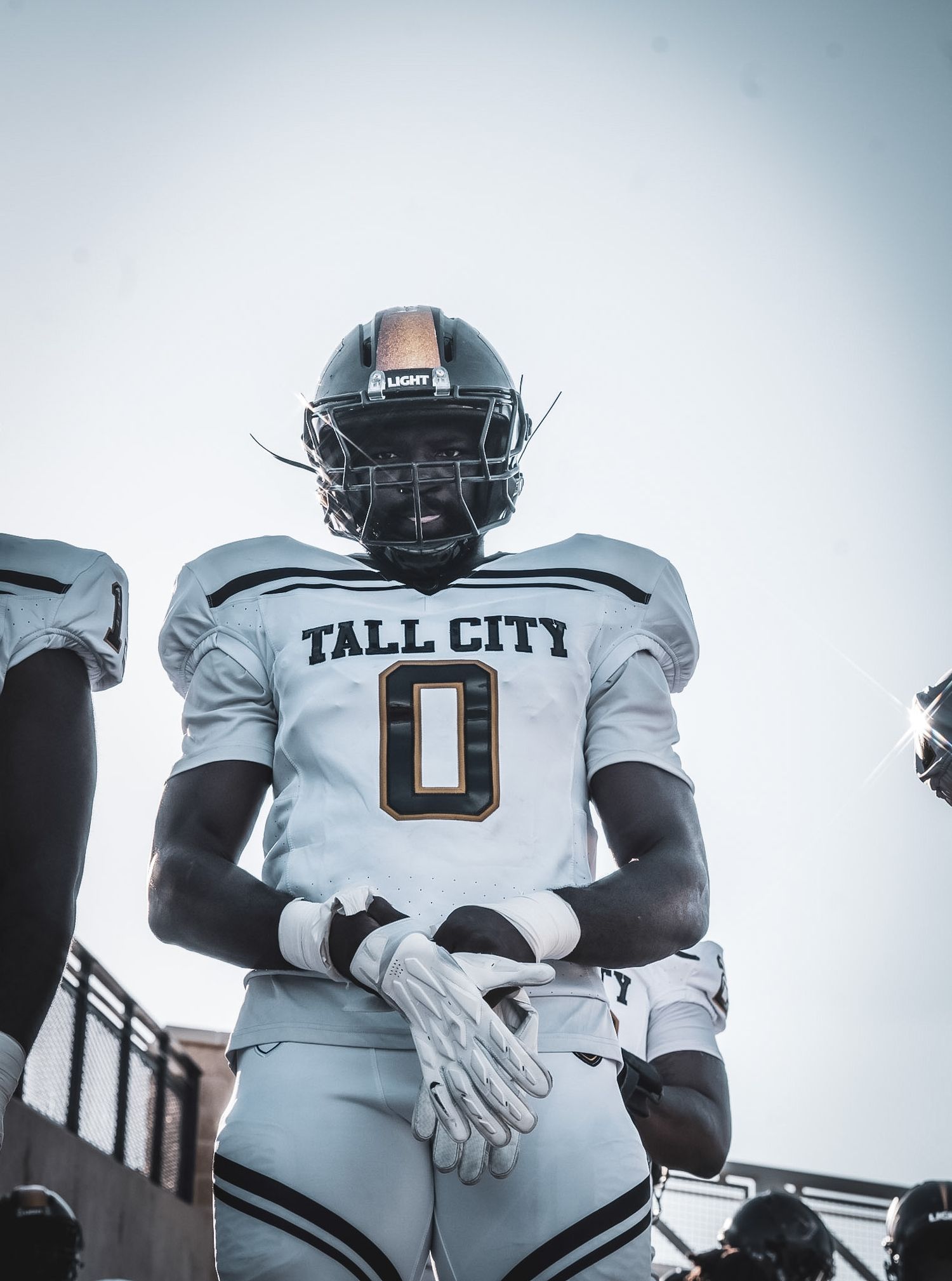 A football player in a white Tall City number 0 jersey and helmet stands ready before a game.
