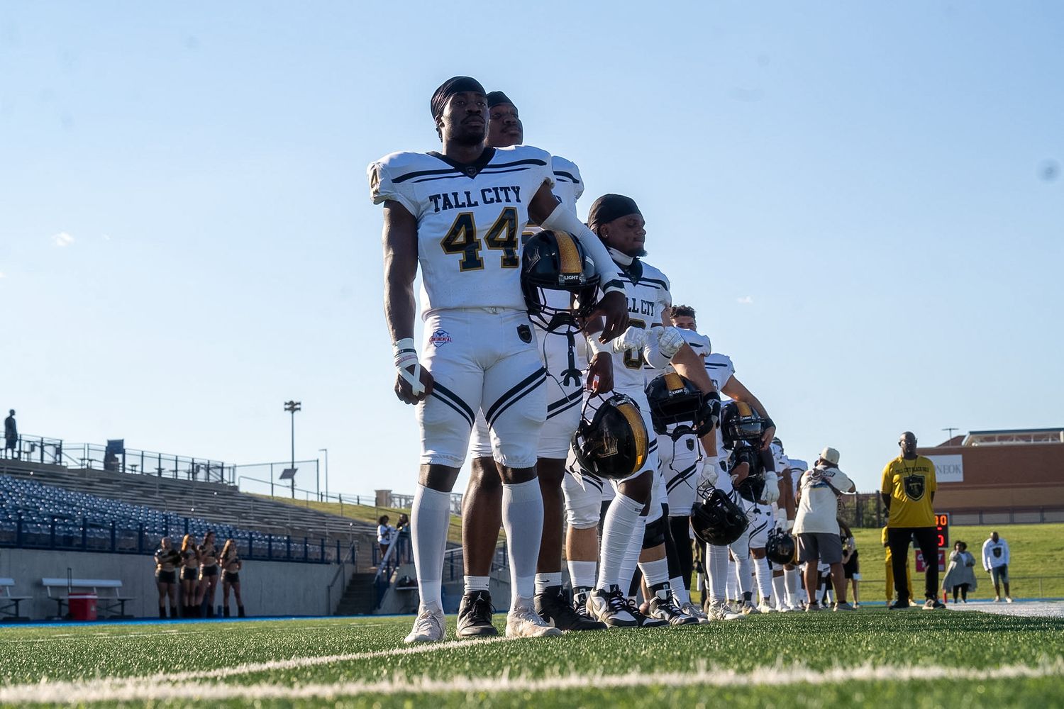 Tall City football player number 44 leads teammates in line on field during game day.