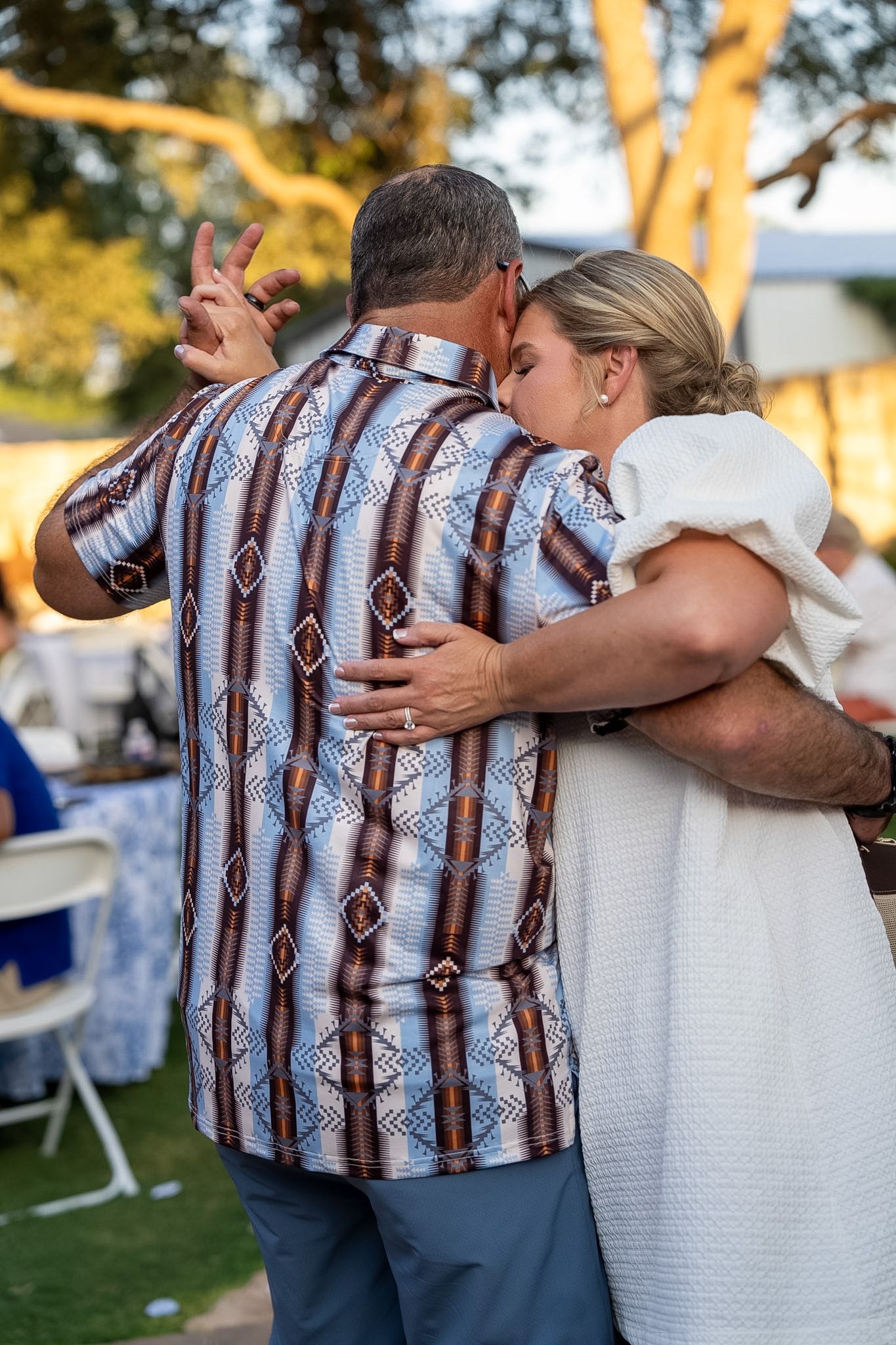 Bride and groom sharing first dance at outdoor wedding reception at sunset.