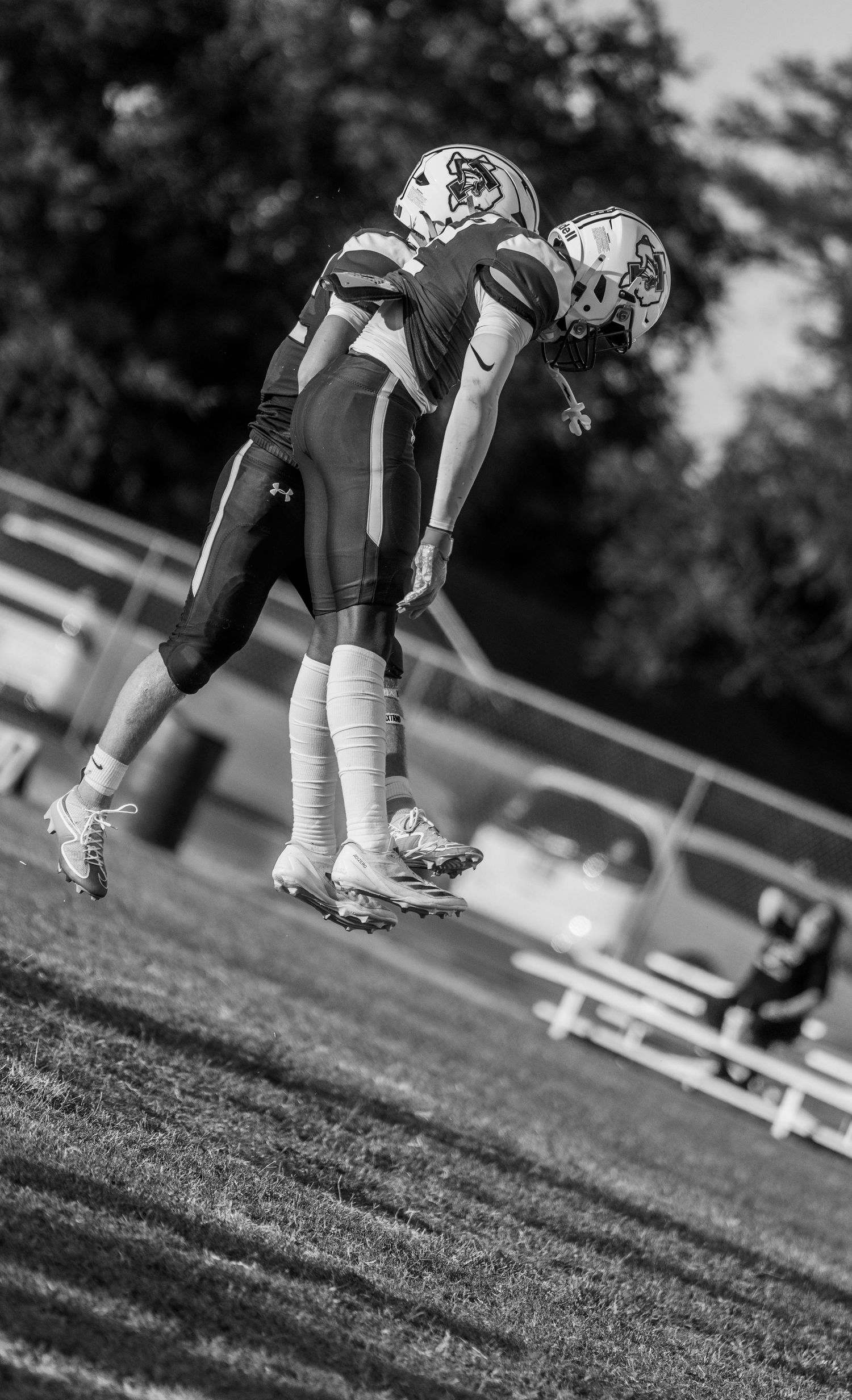 Two football players celebrate on the field in a black and white action photo during a game.