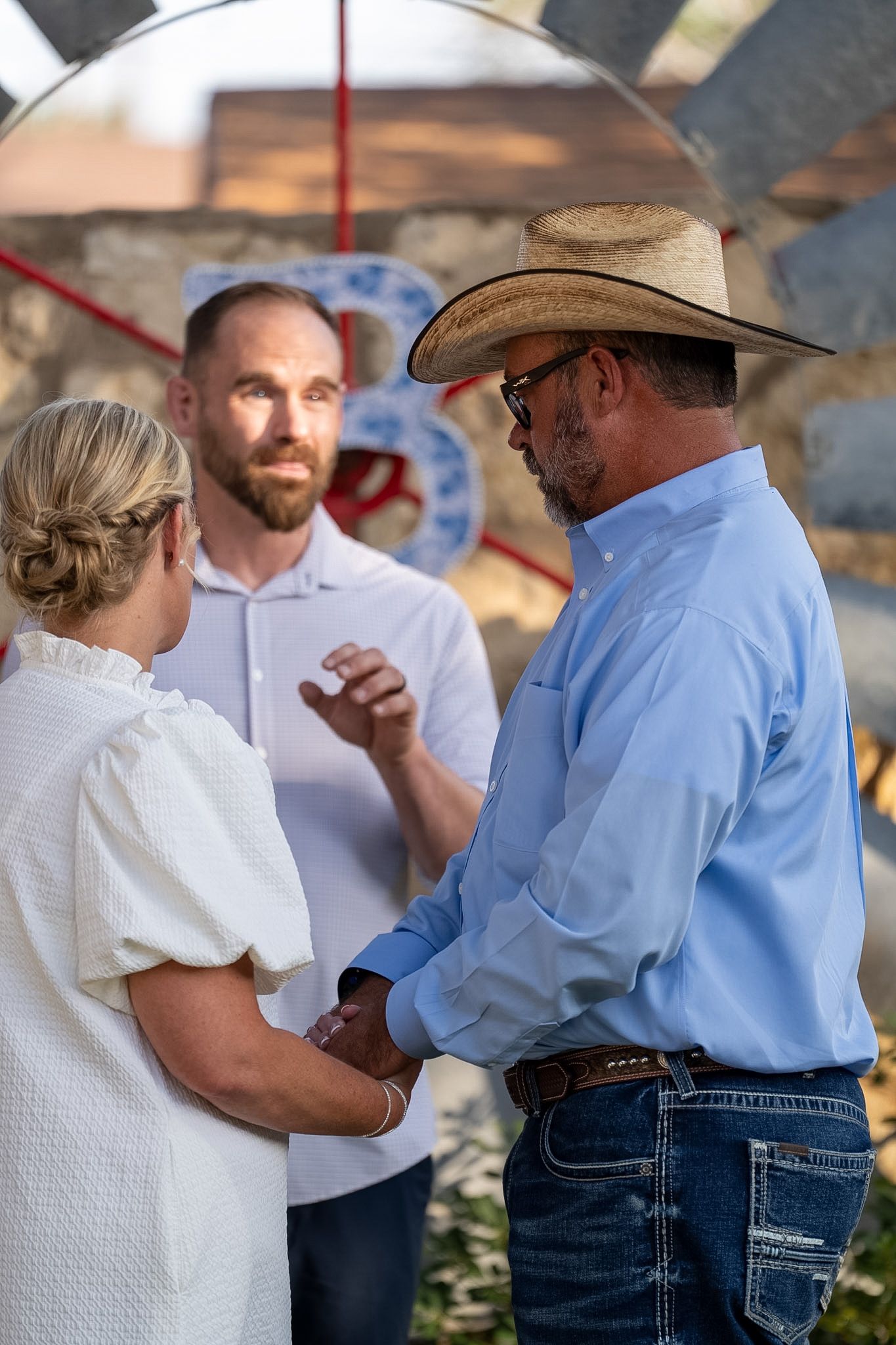 Couple exchanging vows with officiant at rustic outdoor wedding ceremony.