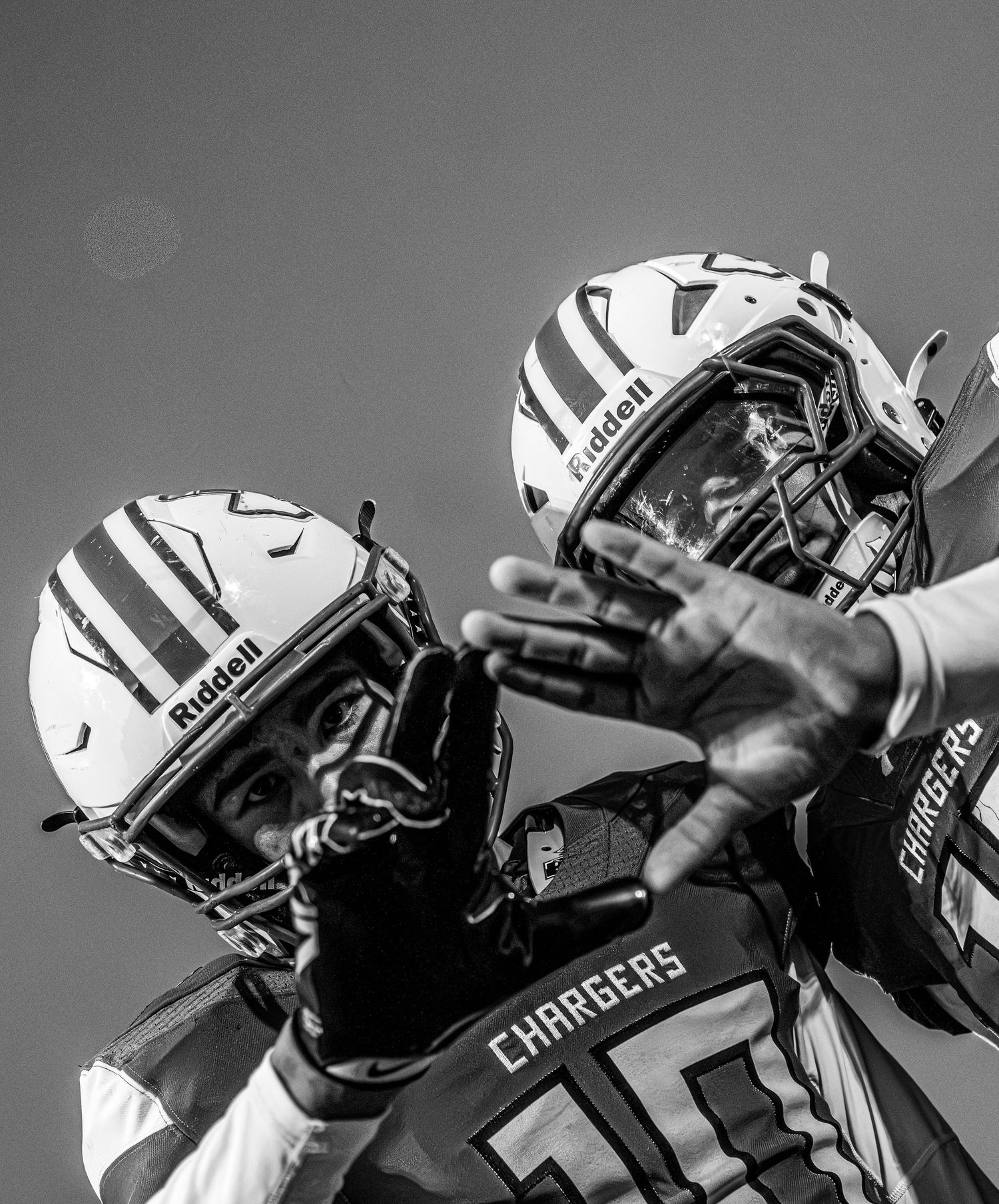Two football players in Riddell helmets and Chargers uniforms celebrate in a dramatic black and white photo.