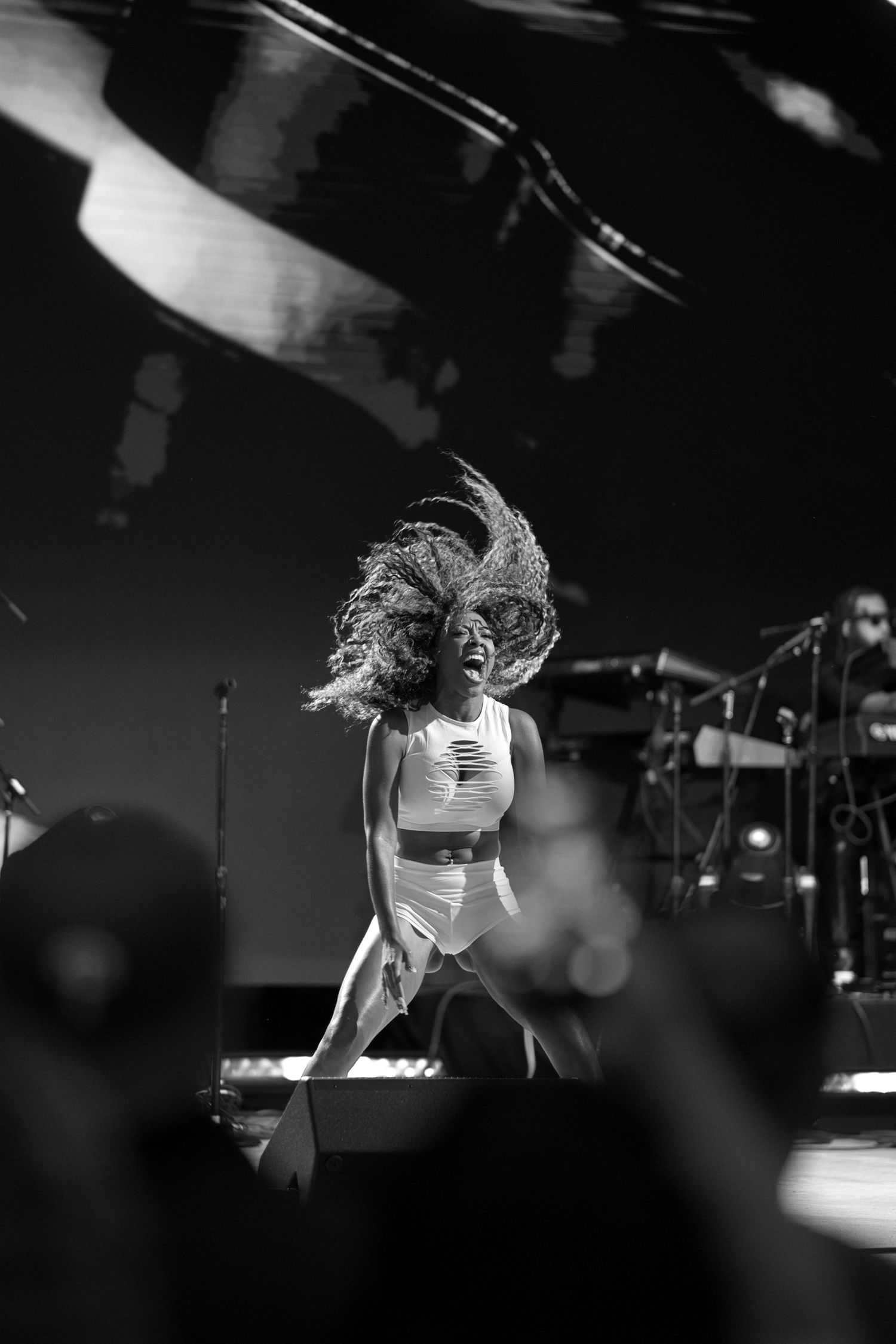 Black and white photo of a performer on stage, hair flying dramatically while dancing energetically before a live crowd.
