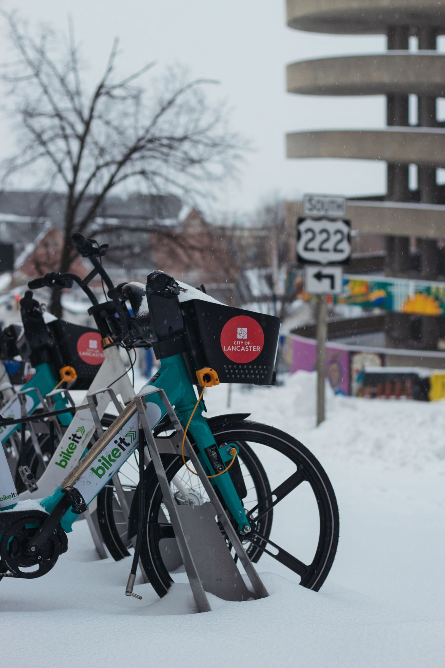 BikeIt share bikes parked in snowy Lancaster, PA near Route 222 sign during winter.