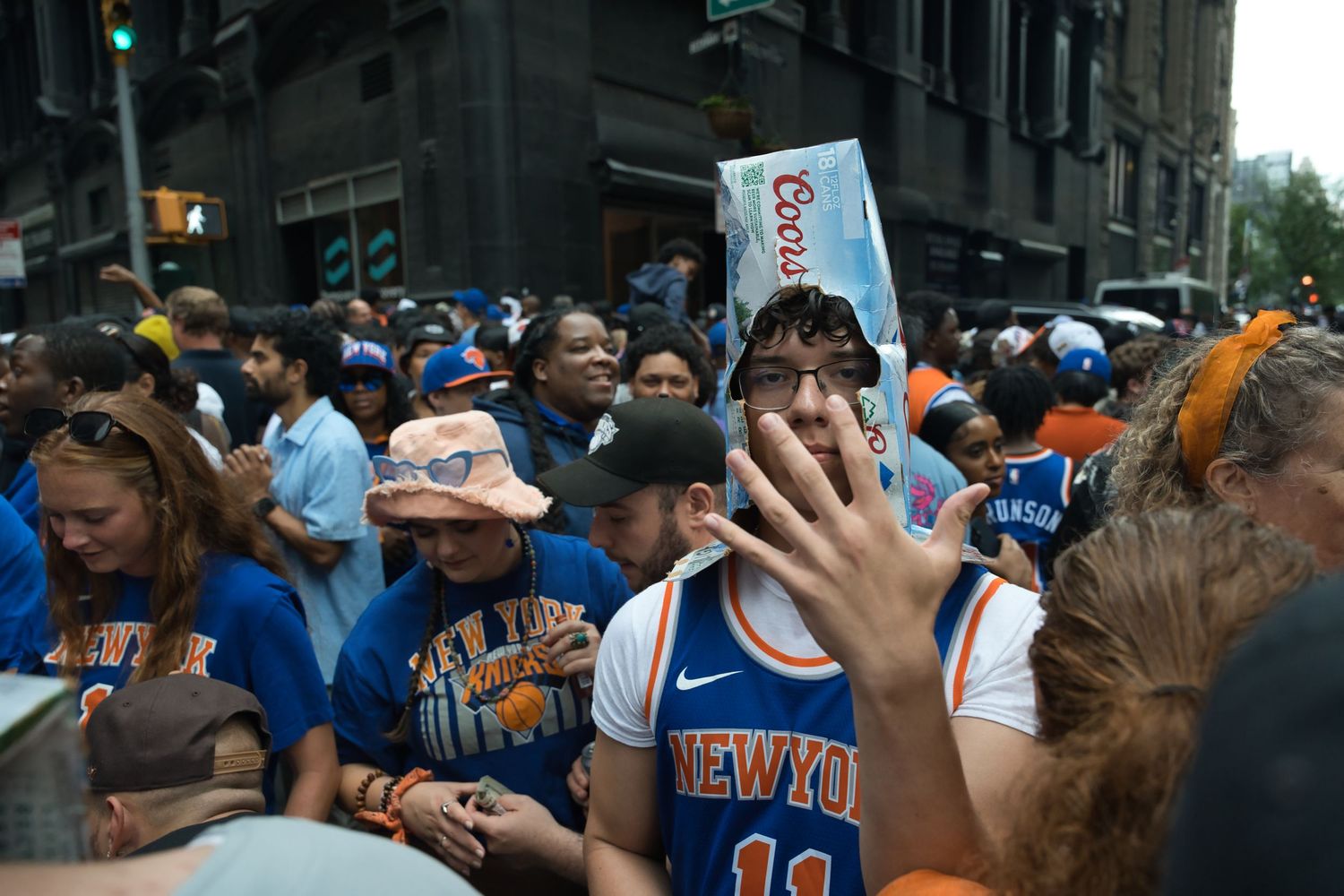 Crowd of New York Knicks fans in orange and blue jerseys at street parade.