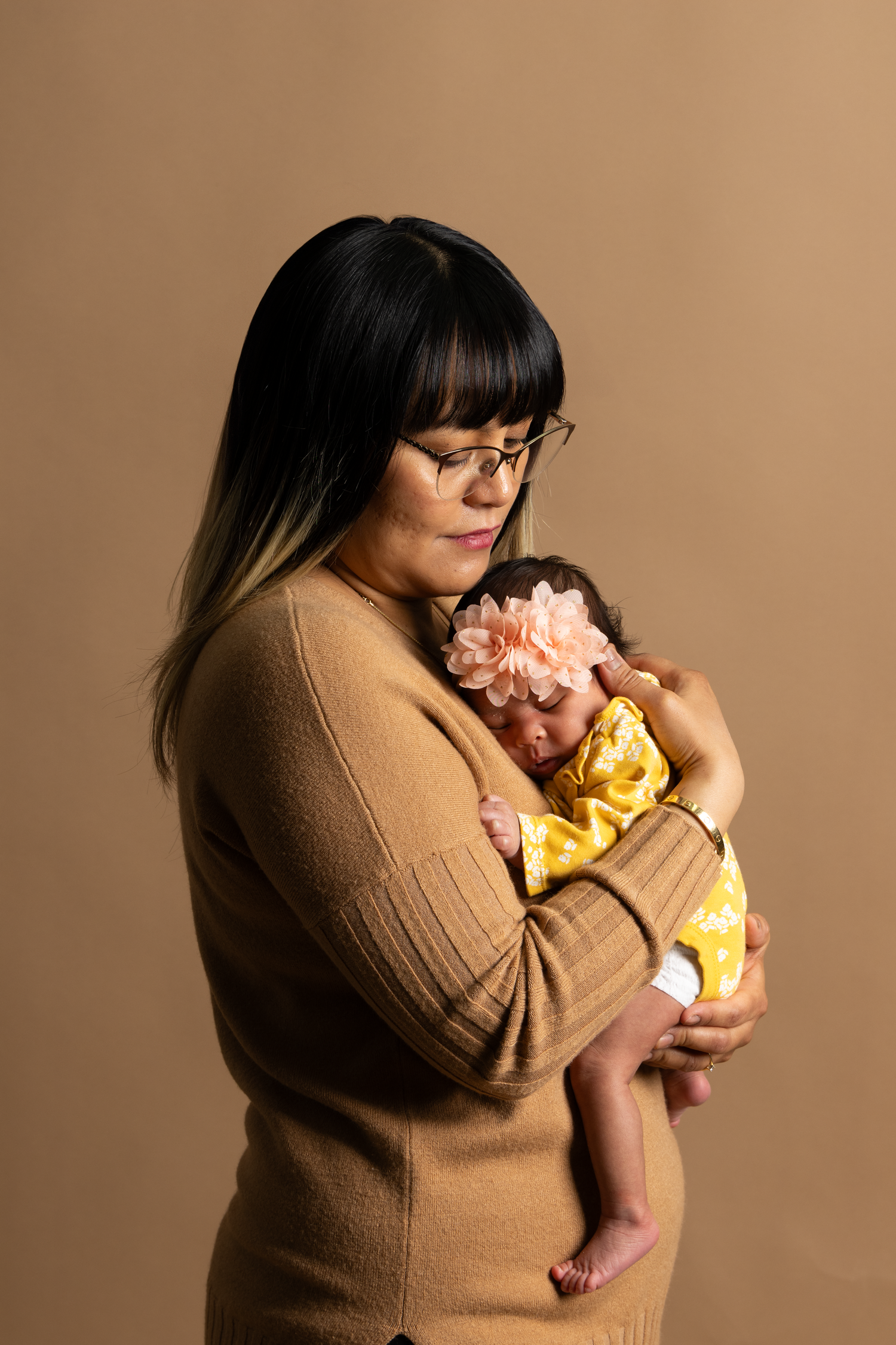 Mother holding her newborn baby during a natural pose in a studio portrait session.