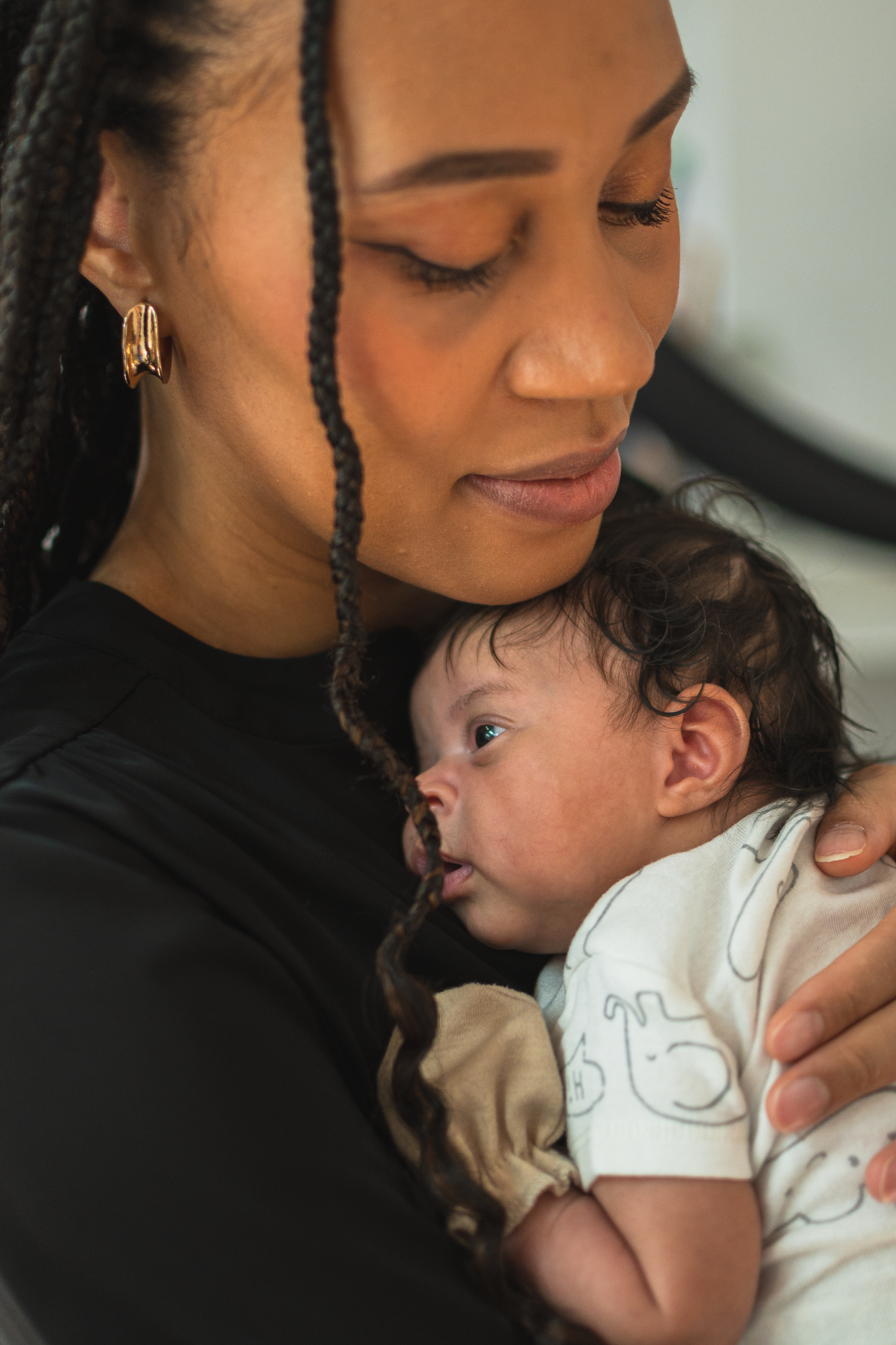 Mother holding her newborn baby during a natural moment in between a studio portrait session.