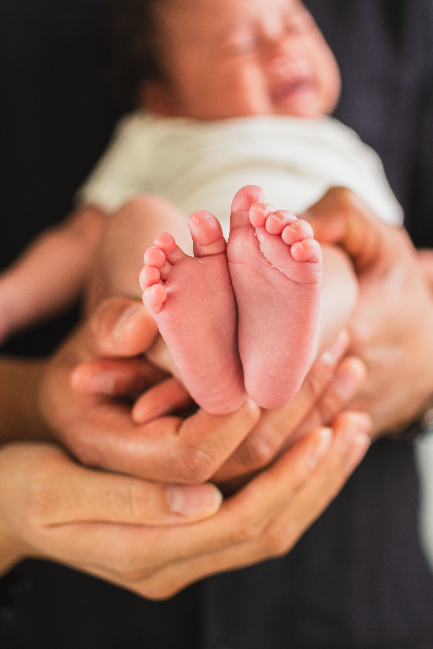 Parents holding their newborn baby, showing her cute feet during a lifestyle studio session in Edmonton.

creative shot