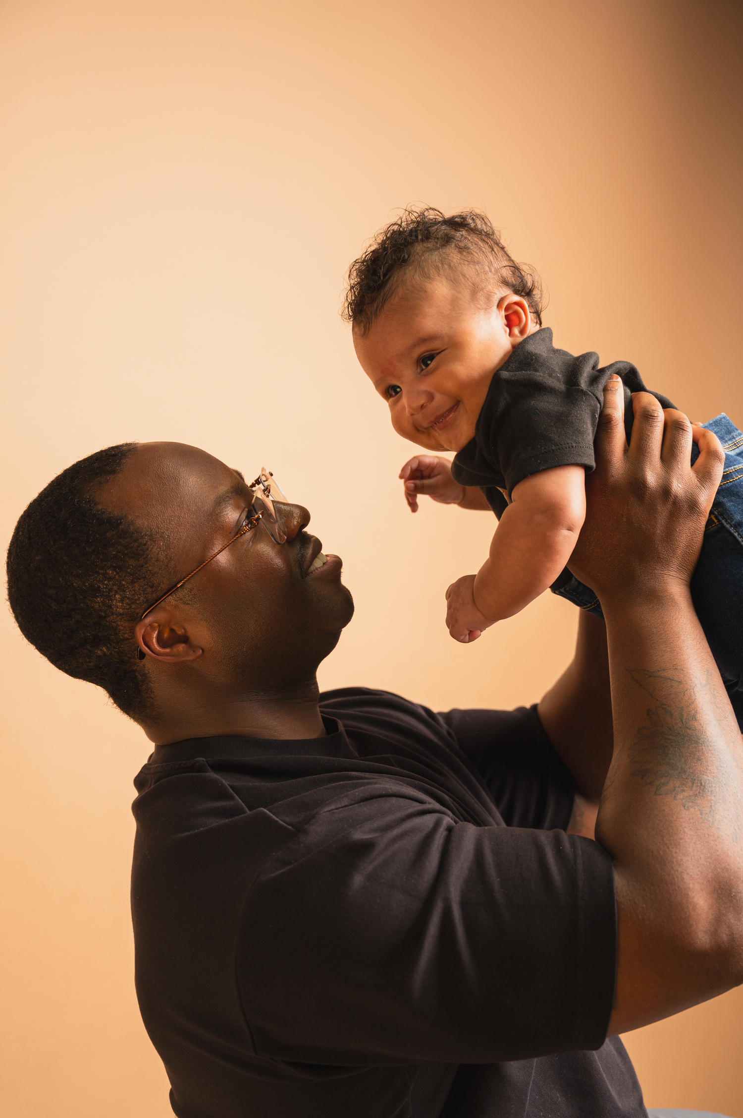 Father holding his newborn baby, lifting up profile shot during a studio session in Edmonton.