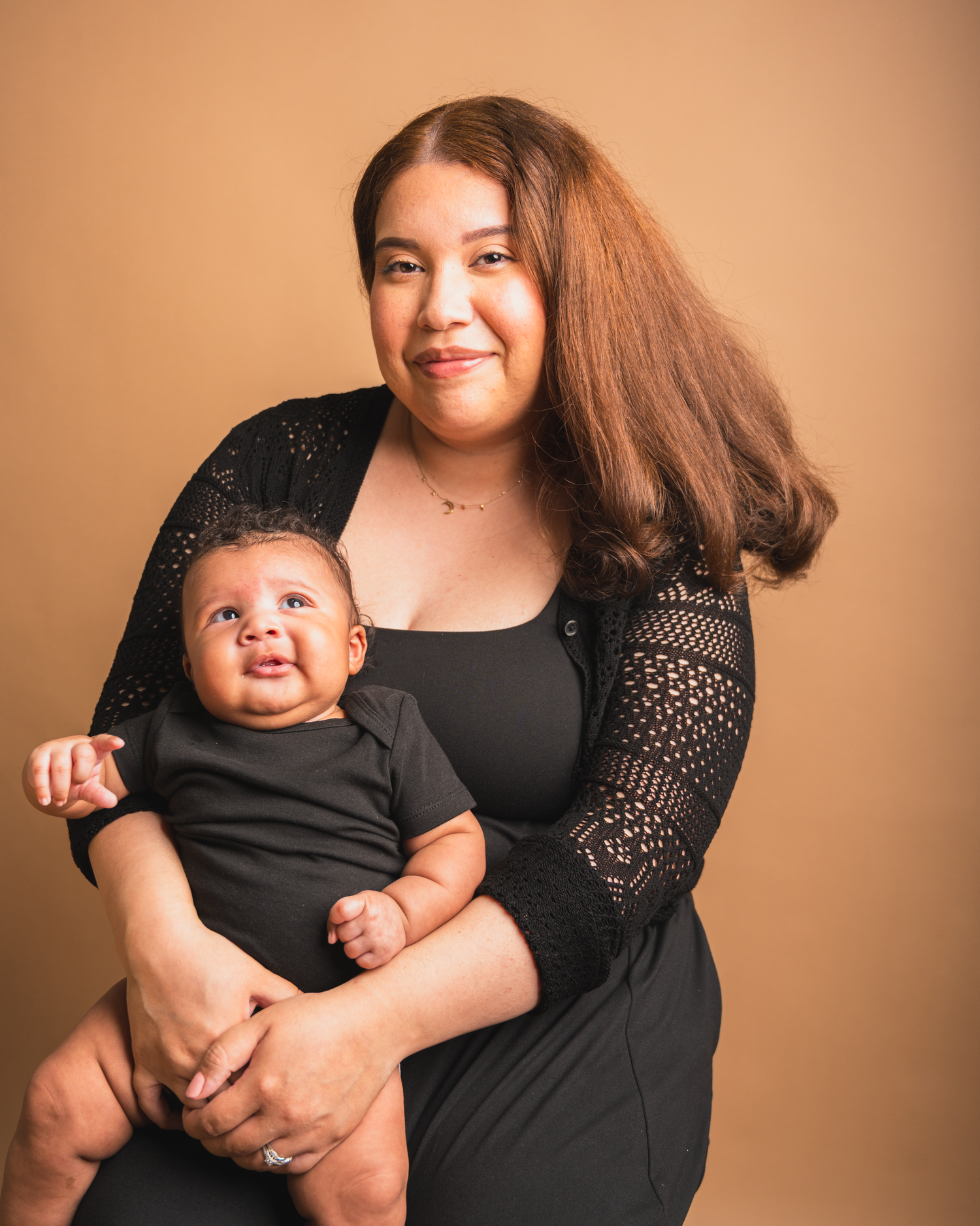 Mother holding her newborn baby in a studio portrait session.