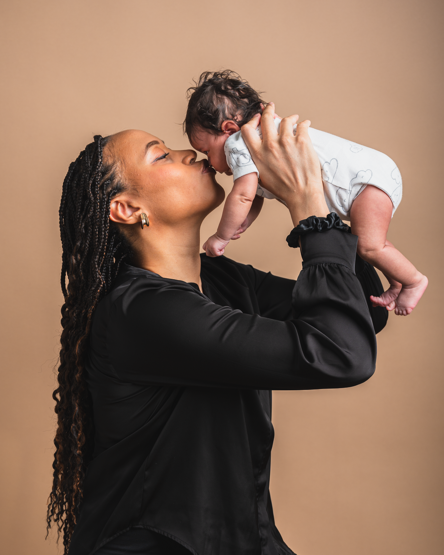 Mother holding up her newborn baby during a natural moment in between a studio portrait session.