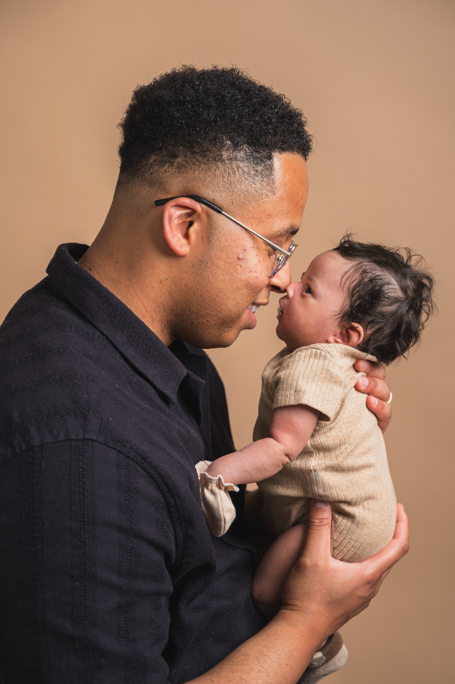 Father holding his newborn baby, nose-to-nose profile shot during a studio session in Edmonton.