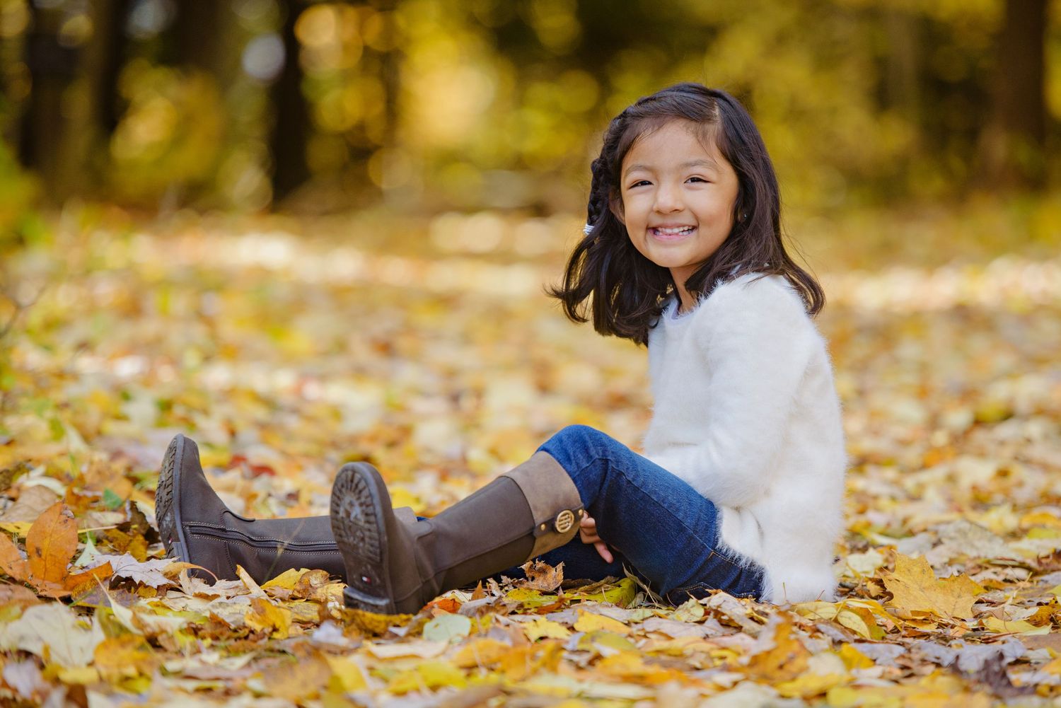 A young child sits in colorful autumn leaves during a fall photo session at Cuyahoga Valley National Park in Peninsula Ohio.