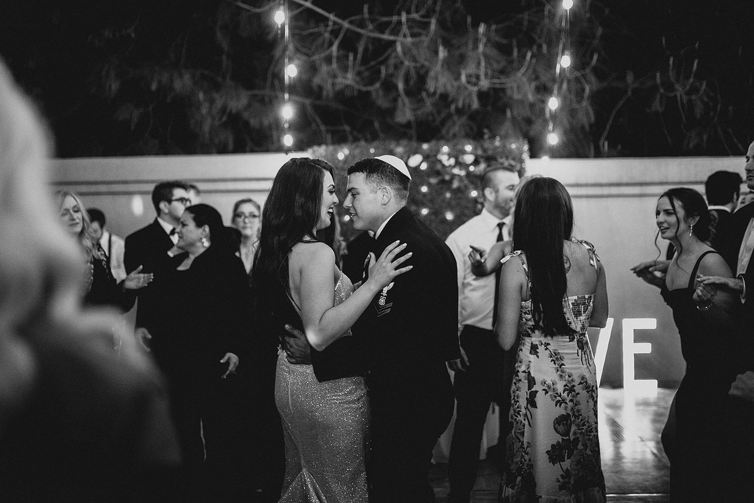 Wedding guests dance together during an evening reception celebration on the dance floor.