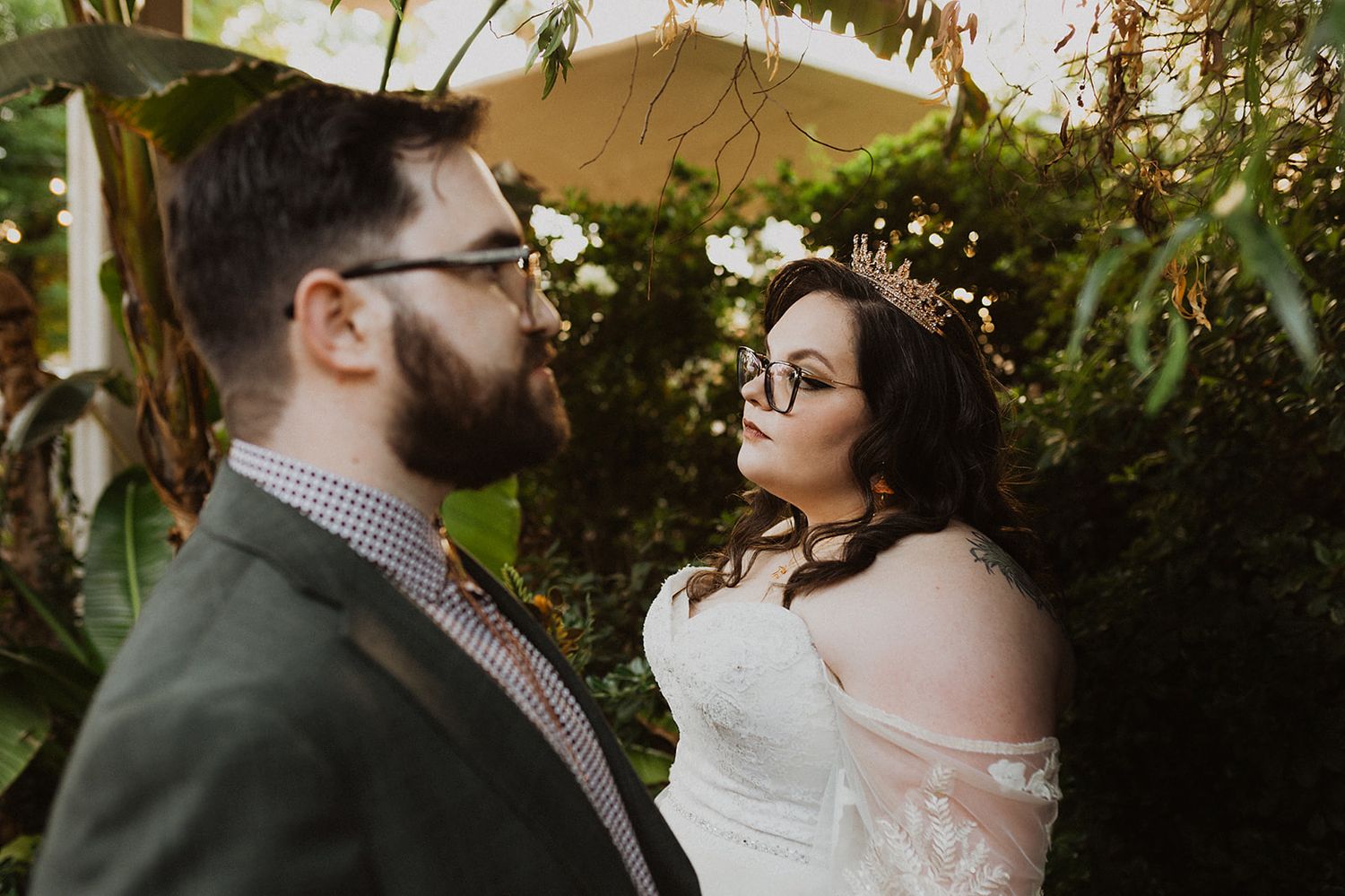 A couple embraces during an intimate outdoor wedding ceremony surrounded by lush greenery and natural light.