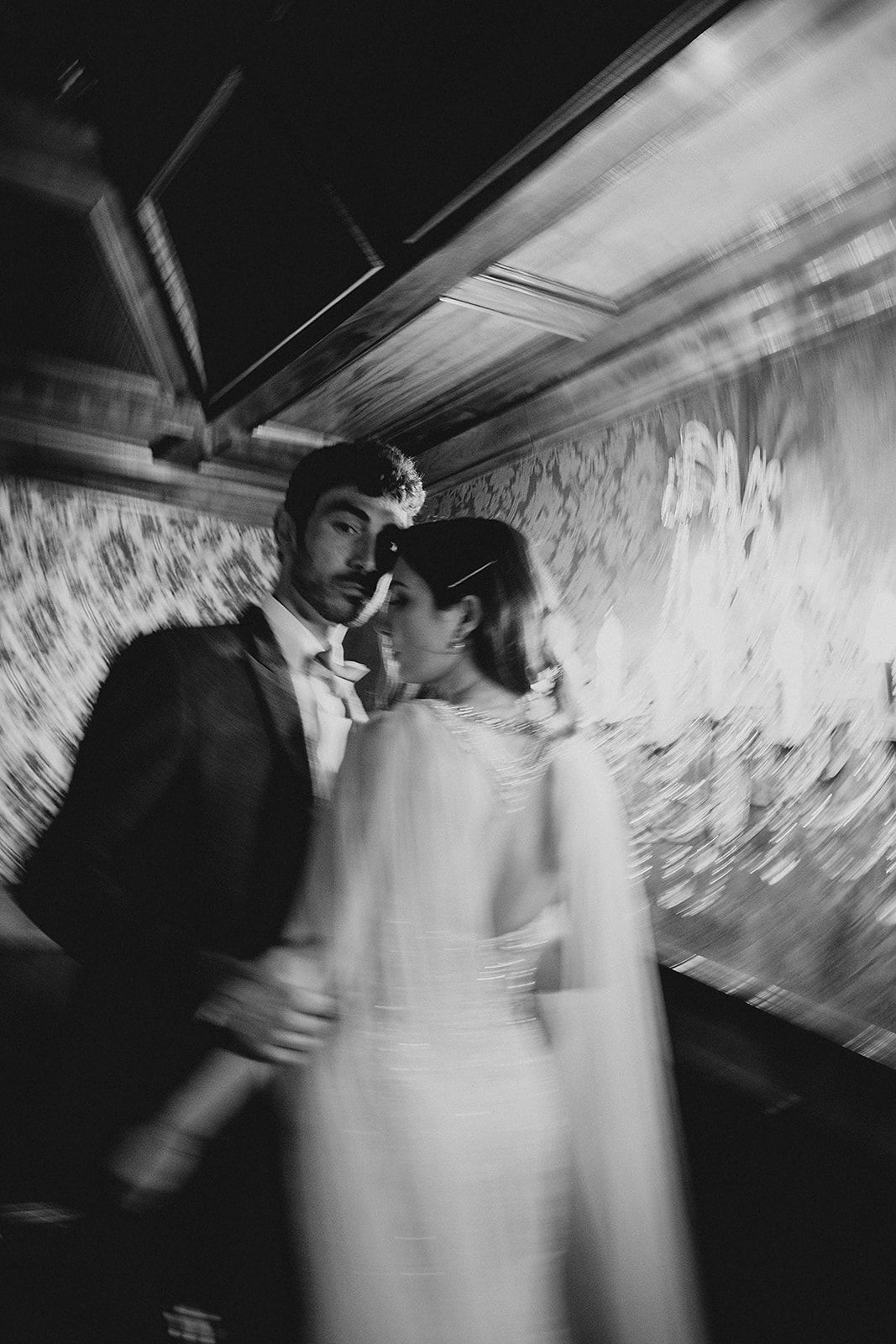 A sequence of blurred black and white motion shots showing dancing figures in a dimly lit space.