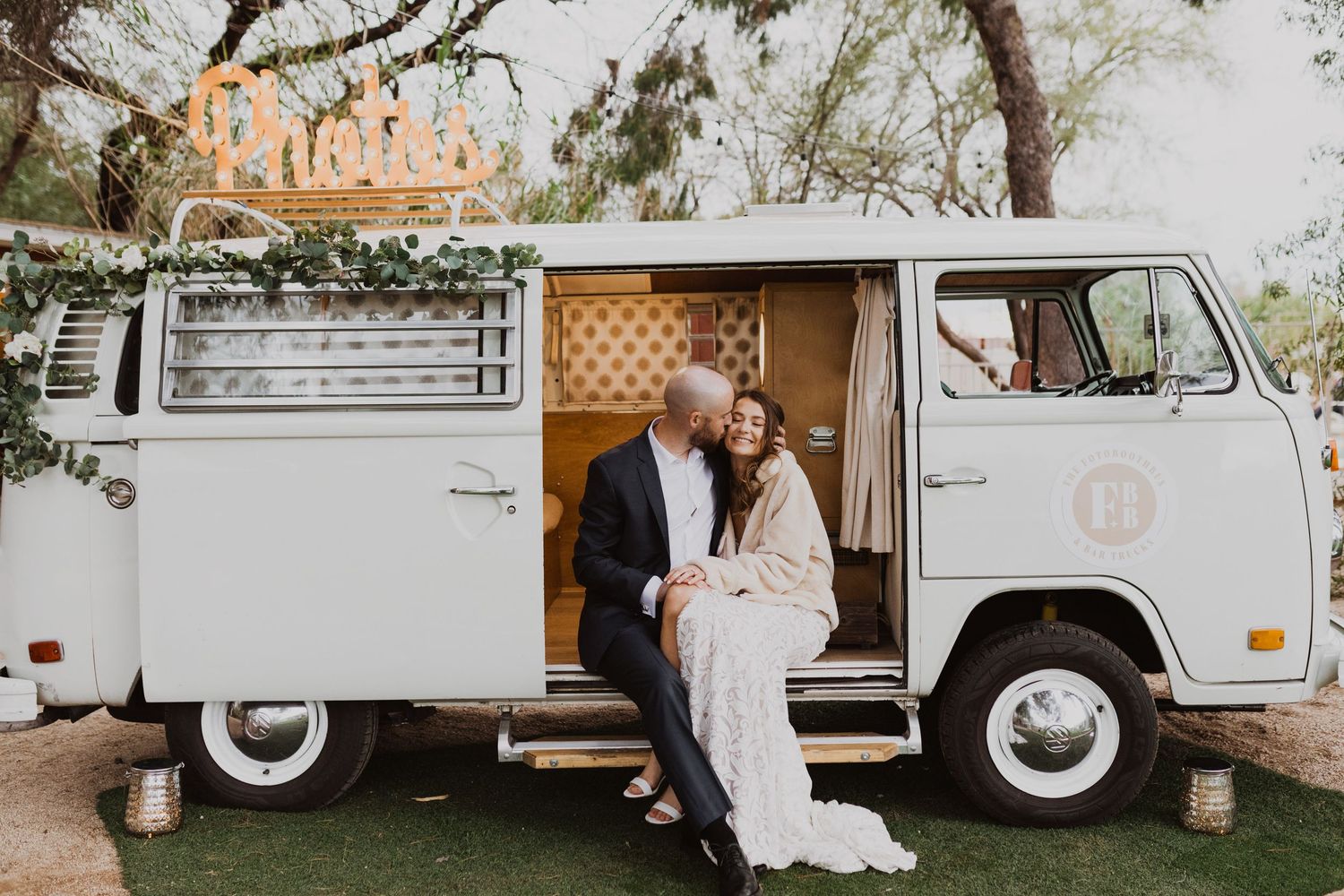 A vintage white Volkswagen van parked outdoors with rustic decor and string lights creating a cozy atmosphere.