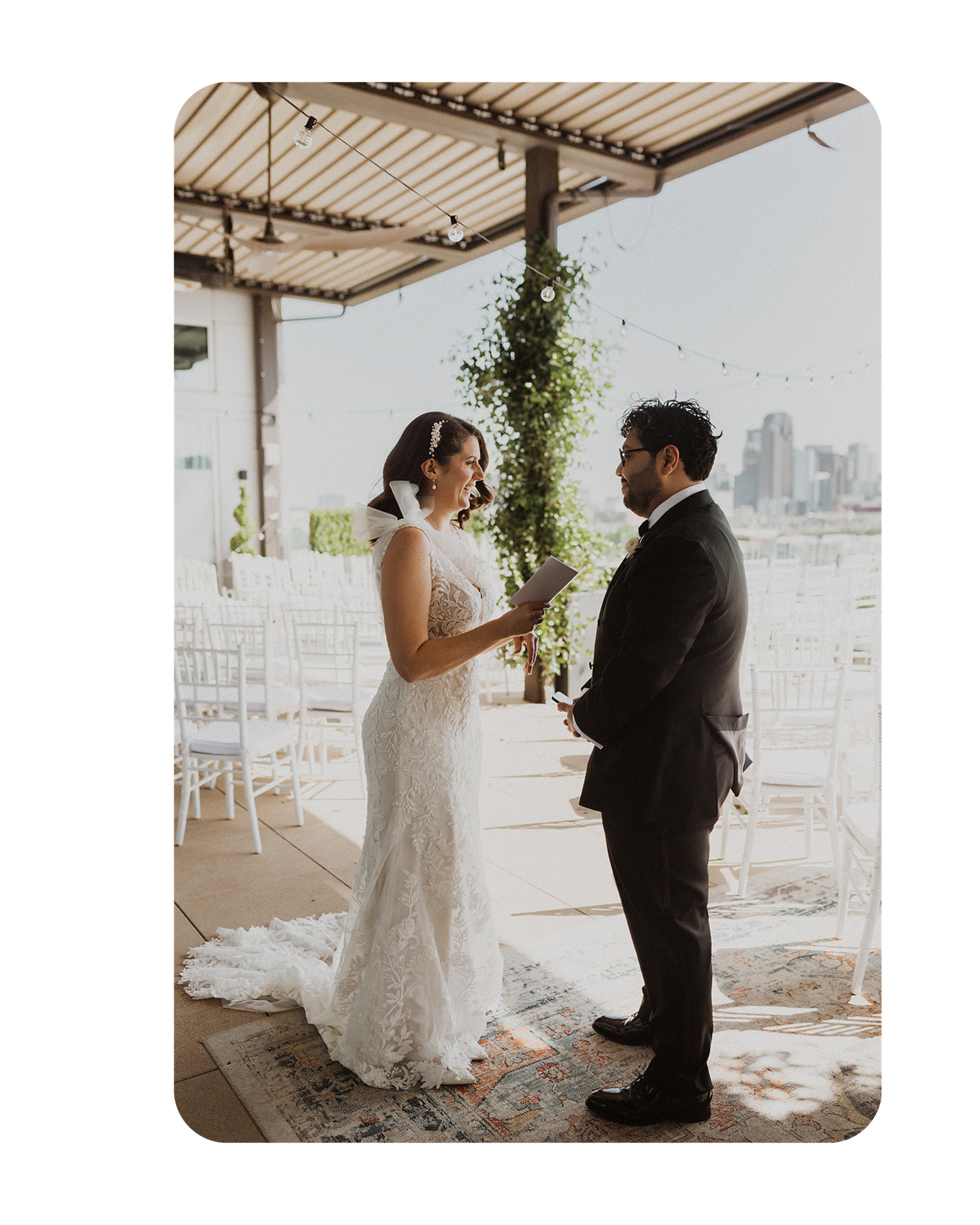 Two people share a private moment during their first look at a rooftop wedding venue with city views in the background.