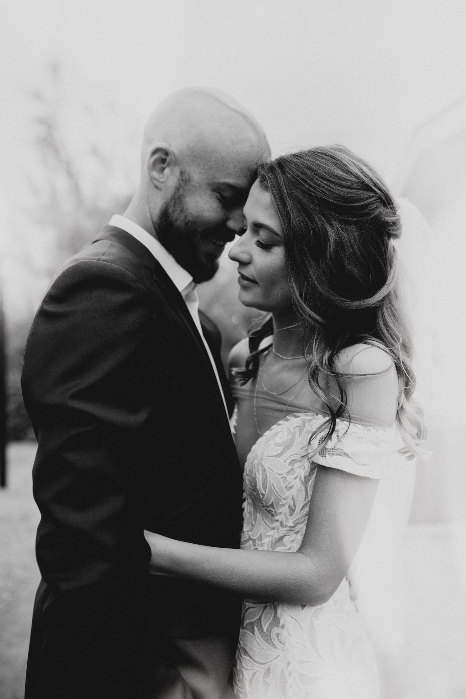A romantic black and white wedding photo series showing tender moments between newlyweds during their outdoor photoshoot.