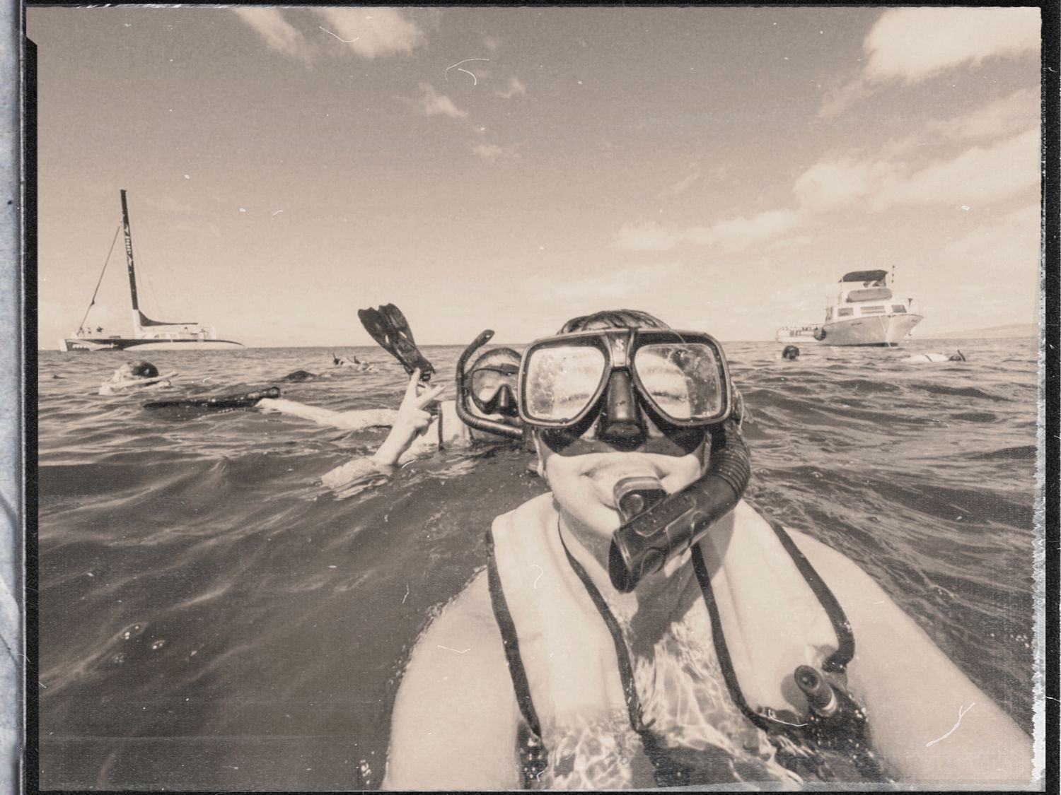 Sepia-toned water sports photography showing boats and snorkeling activities.