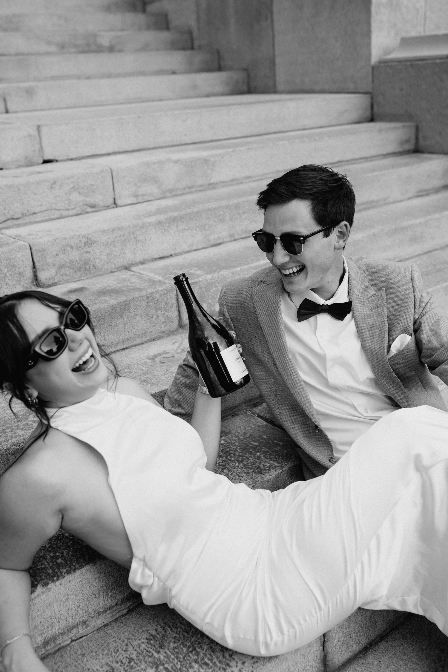 A playful black and white photo series of a couple in wedding attire lounging on stone steps.