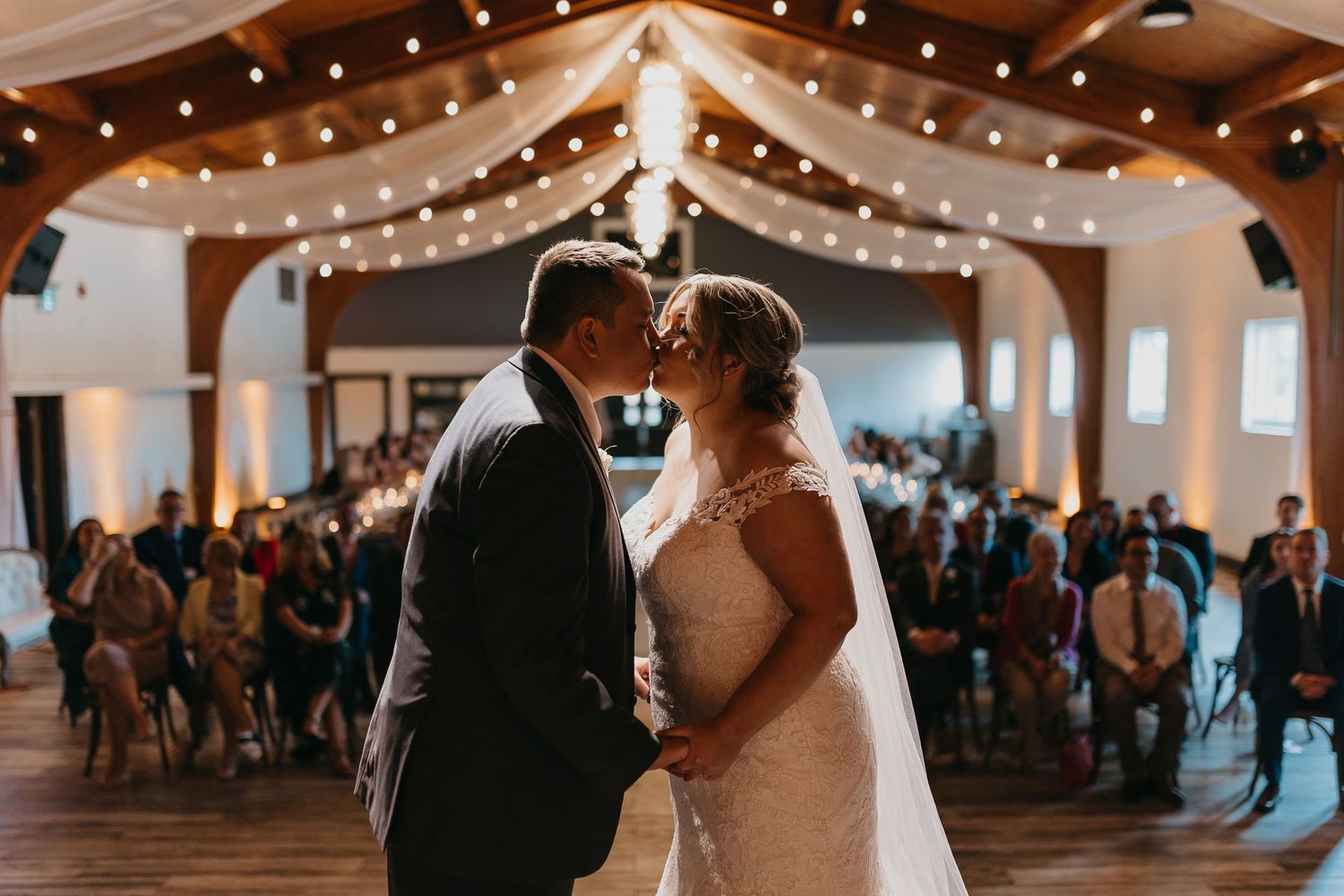 Reception venue decorated with string lights as couple shares intimate moment during celebration.