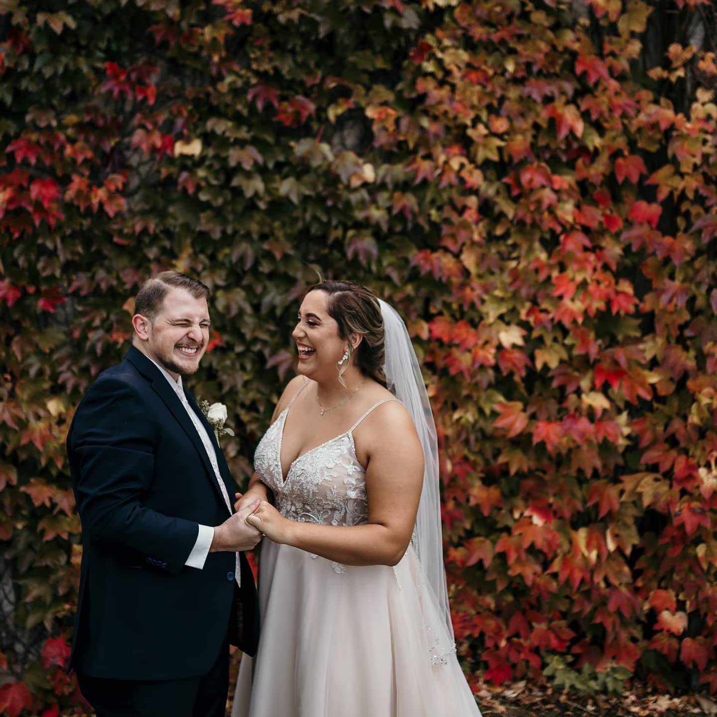 A couple shares a joyful moment against a backdrop of vibrant autumn foliage.